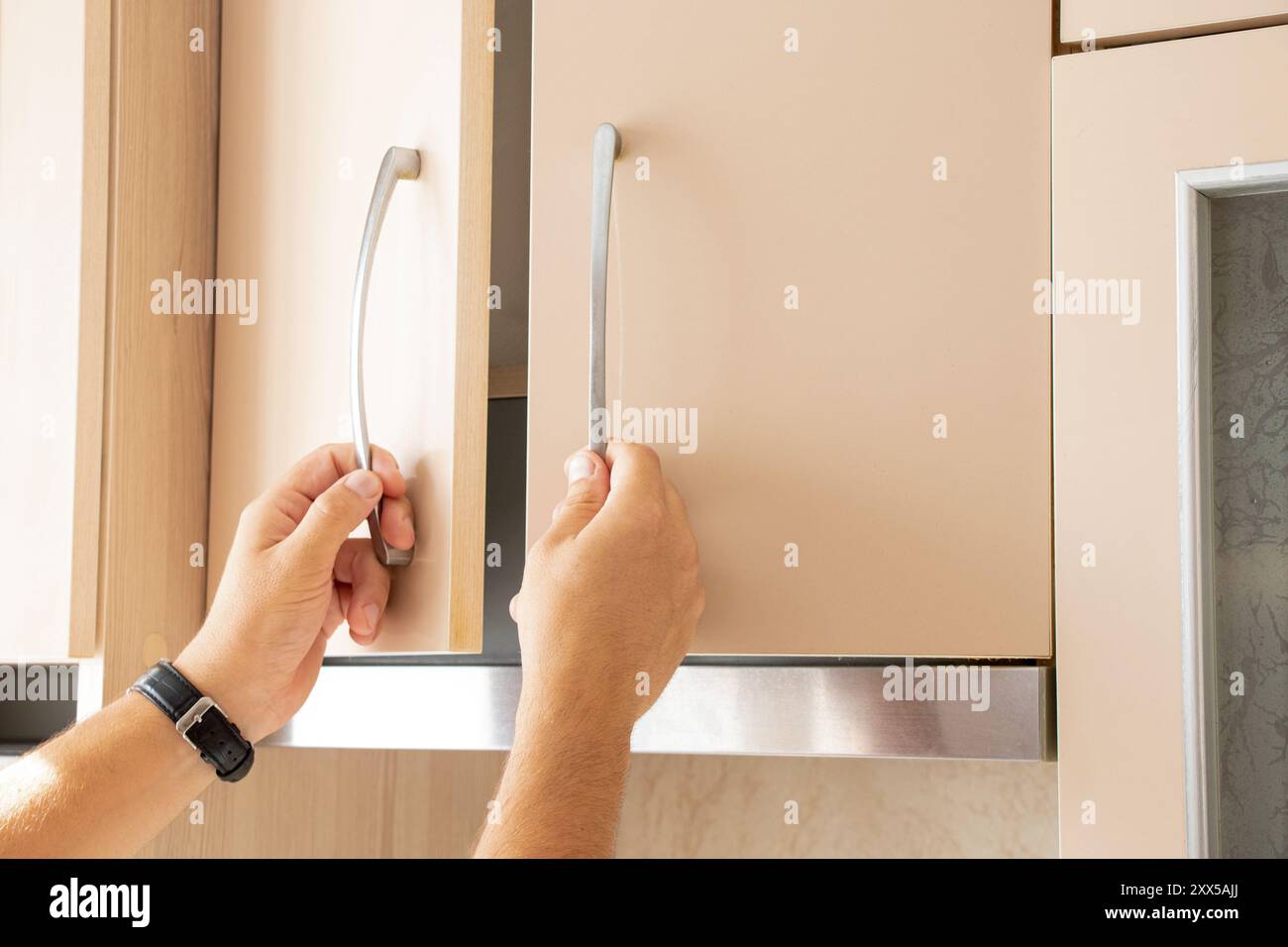 Mani maschili che aprono l'armadio da cucina beige in cucina nell'appartamento, mobili da cucina Foto Stock