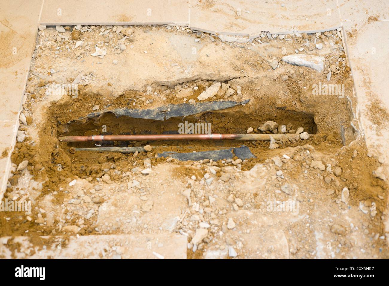 Tubazioni di riscaldamento centralizzato domestico esposte sotto un pavimento piastrellato dopo aver riparato una perdita d'acqua in una casa nel Regno Unito Foto Stock