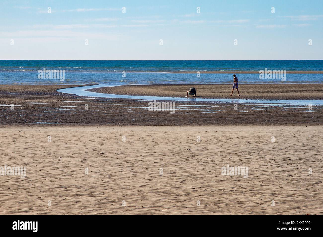 Due persone, un uomo e una donna che si godono la giornata in spiaggia. Smal creek sulla spiaggia. Puerto Peñasco, Sonora, Messico. Foto Stock