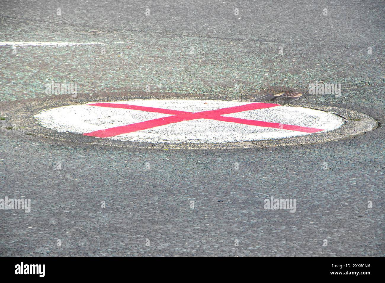 Segnaletica stradale circolare su asfalto con una "X" rossa, bandiera inglese o simbolo St George Cross Foto Stock