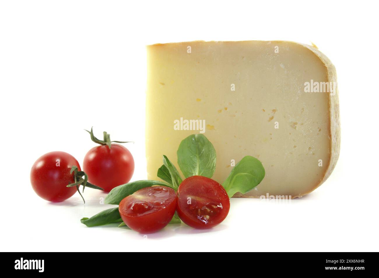Un pezzo di formaggio con pomodori e lattuga di agnello su sfondo bianco Foto Stock