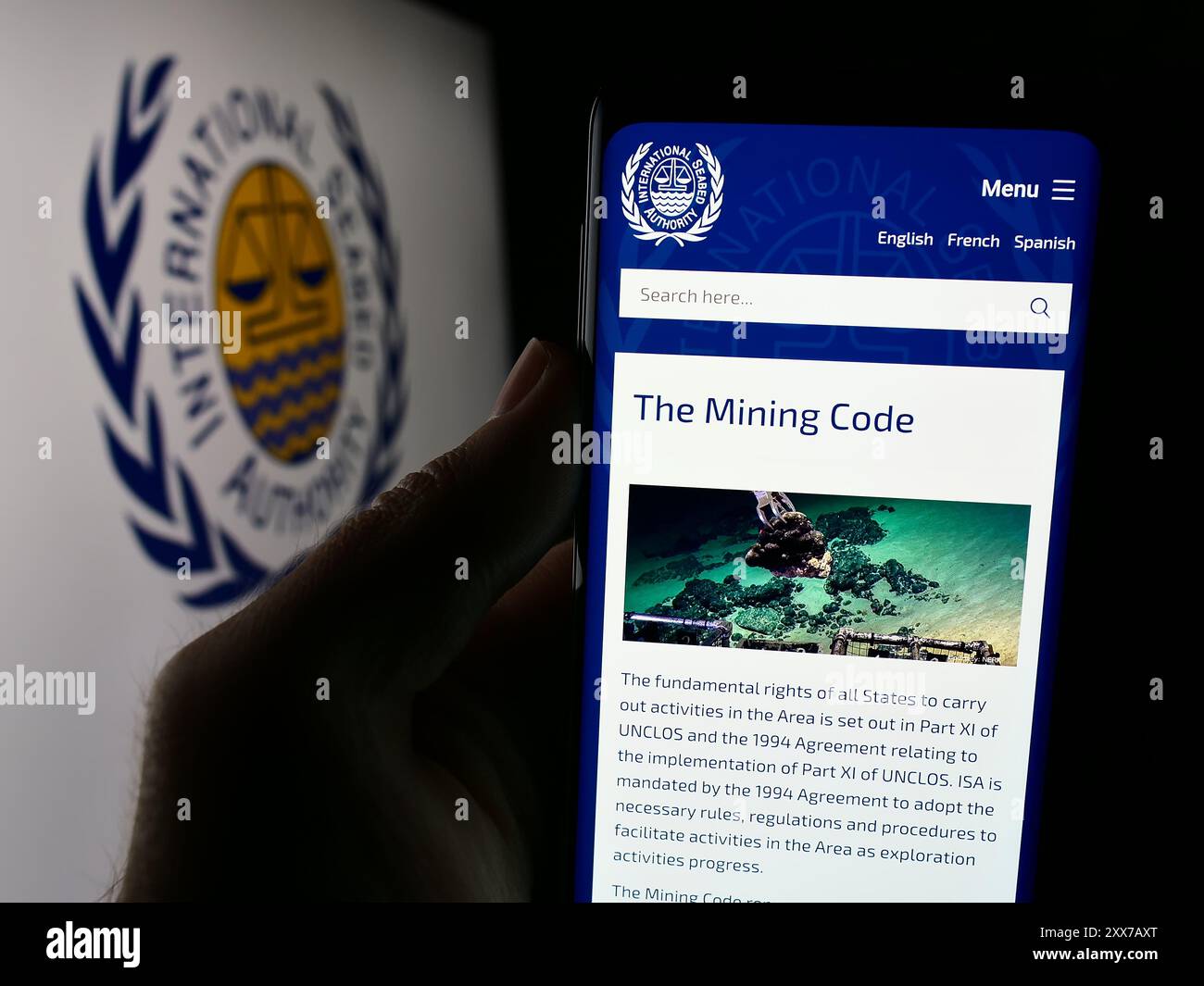 Persona che detiene un cellulare con pagina web dell’organizzazione International Seabed Authority (ISA) davanti al logo. Messa a fuoco al centro del display del telefono. Foto Stock