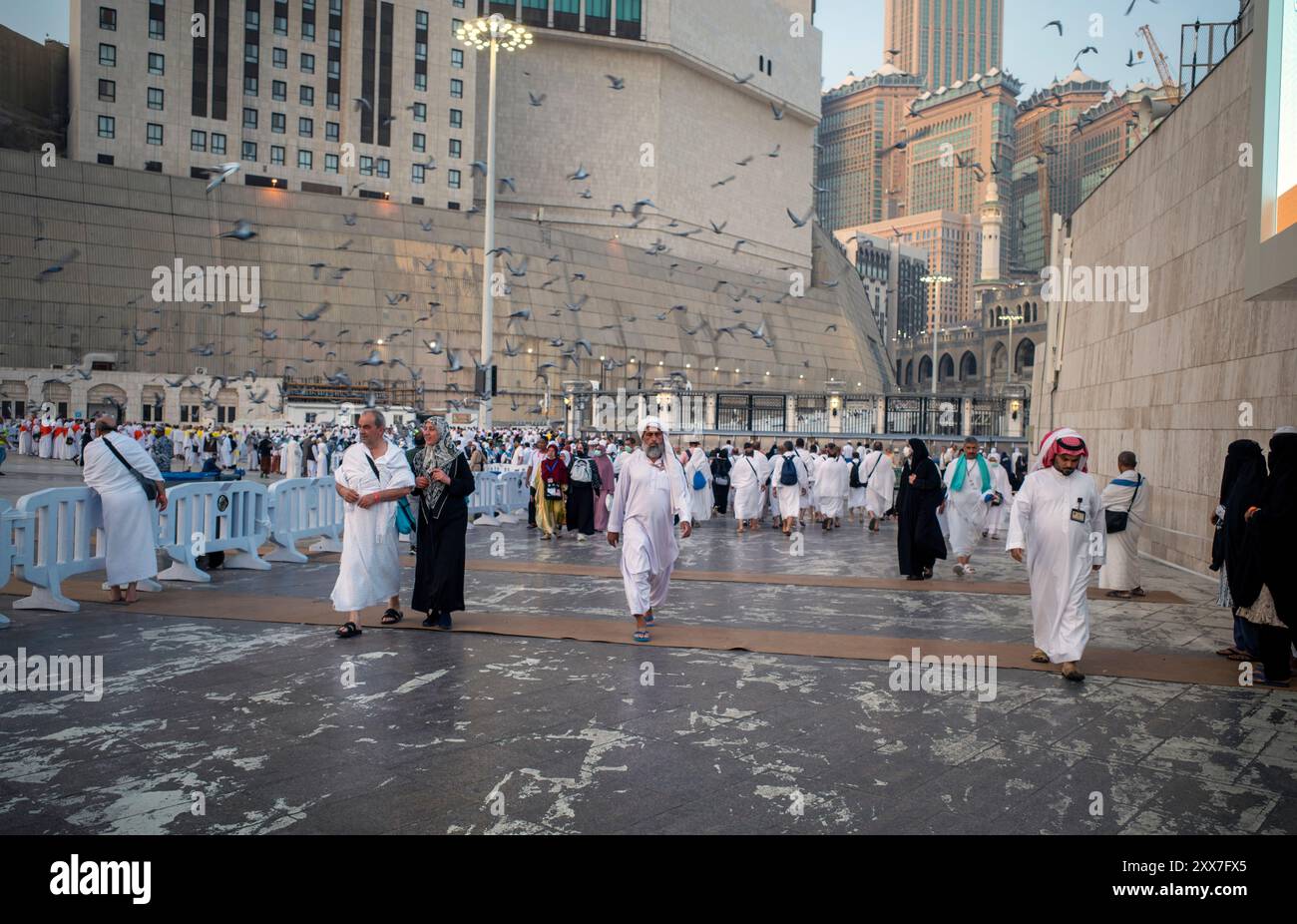 La Mecca, Arabia Saudita - 4 giugno 2024: Pellegrini Hajj e Umrah da tutto il mondo che camminano vicino a Masjidil Haram, grande Moschea della Mecca, con un orologio Foto Stock