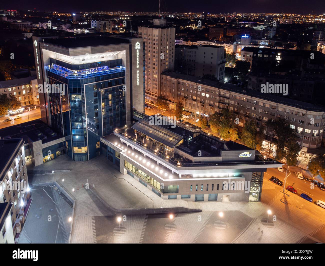 Moderno edificio notturno con facciata in vetro illuminata sulla Piazza della libertà nel centro di Kharkiv, Ucraina Foto Stock