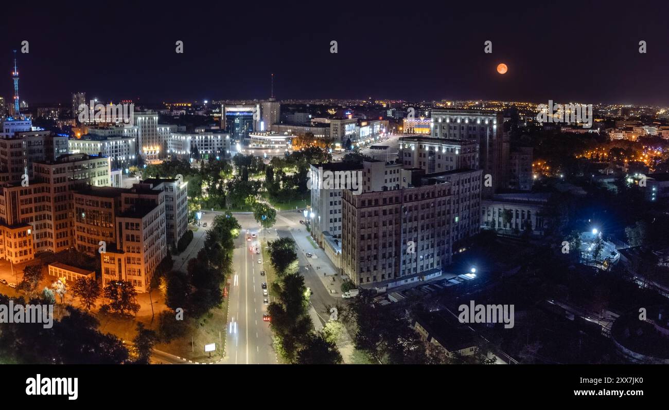 Veduta notturna illuminata della città di Piazza della libertà con gli edifici dell'Università Nazionale di Derzhprom e Karazin dalla discesa di Klochkivskyj a Khar Foto Stock