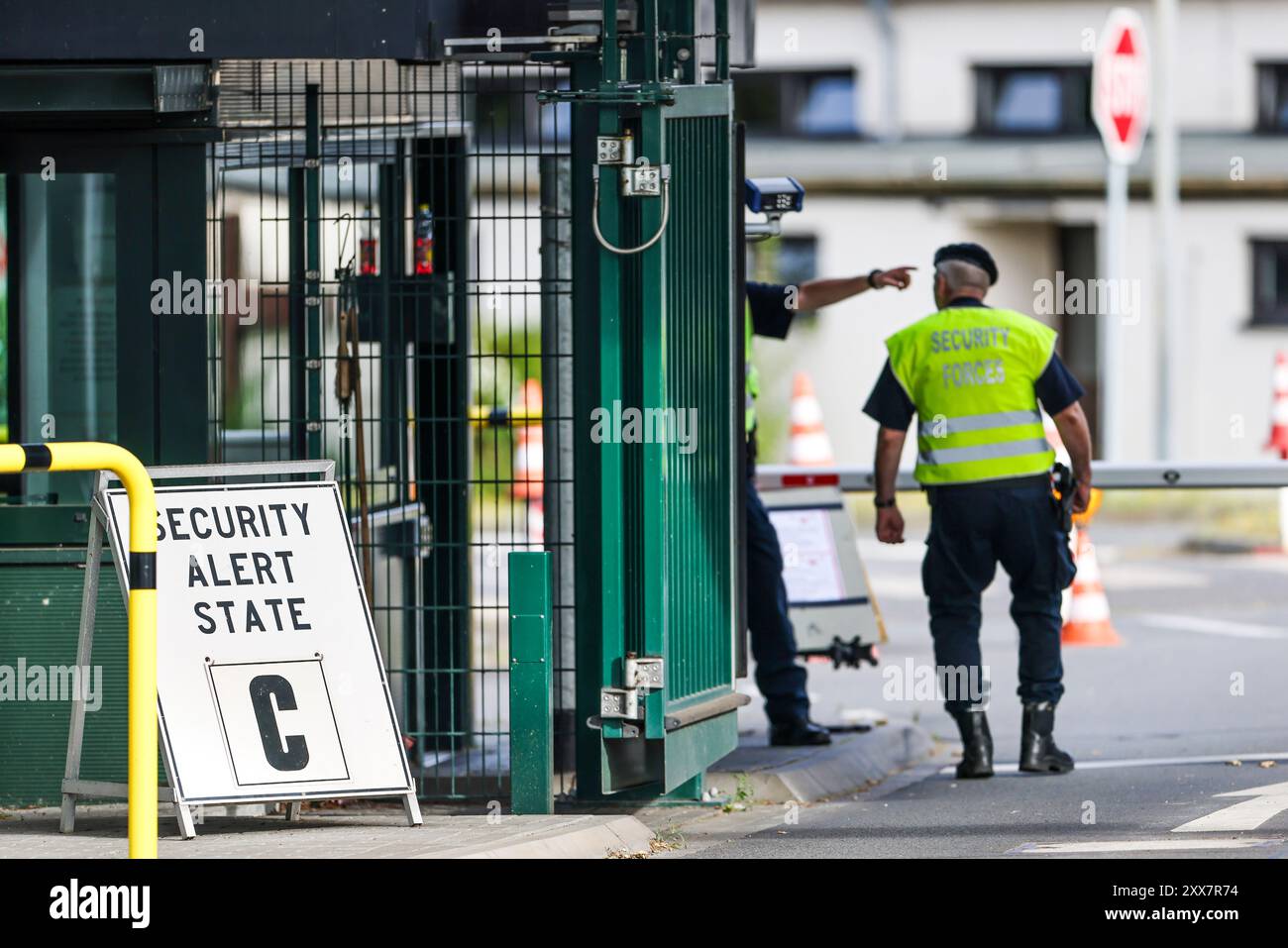 Geilenkirchen, Germania. 23 agosto 2024. Il personale addetto alla sicurezza si trova all'ingresso della base aerea NATO, sulla sinistra il cartello per lo stato C. la NATO aveva dichiarato il secondo livello di allerta più alto nella sua base aerea a Geilenkirchen, Renania settentrionale-Vestfalia. Crediti: Christoph Reichwein/dpa/Alamy Live News Foto Stock