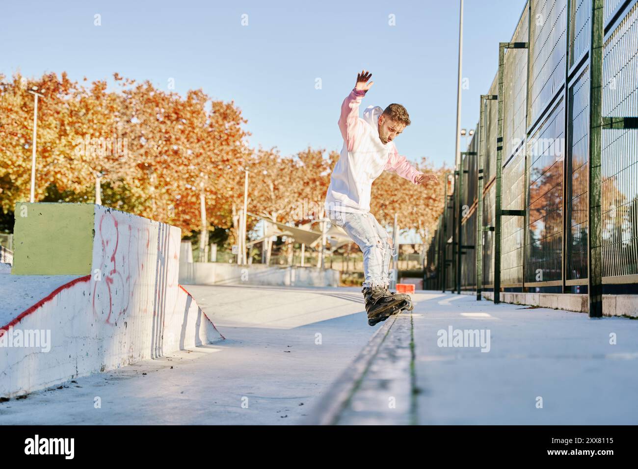 pattinatore aggressivo che esegue un trucco su una ringhiera nello skatepark Foto Stock