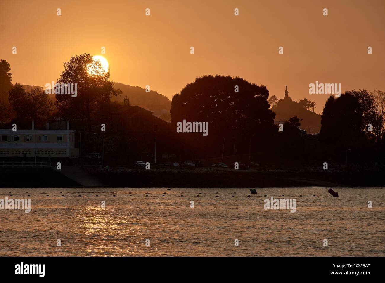 Tramonto unico a Ladeira Beach, dove il sole tramonta dietro un albero solitario, creando una silhouette impressionante contro il cielo serale Foto Stock