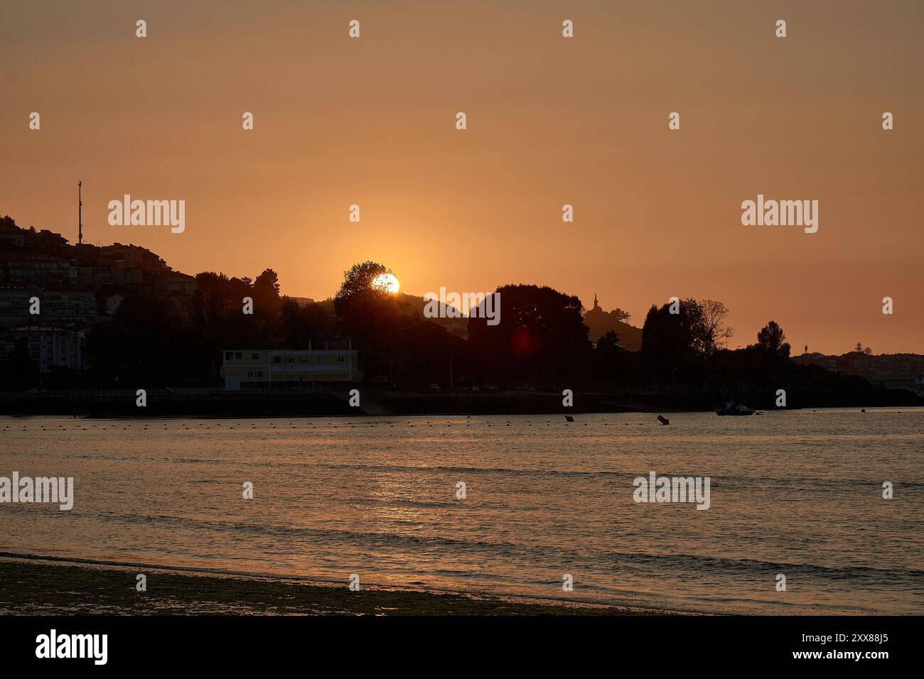 Tramonto unico a Ladeira Beach, dove il sole tramonta dietro un albero solitario, creando una silhouette impressionante contro il cielo serale Foto Stock