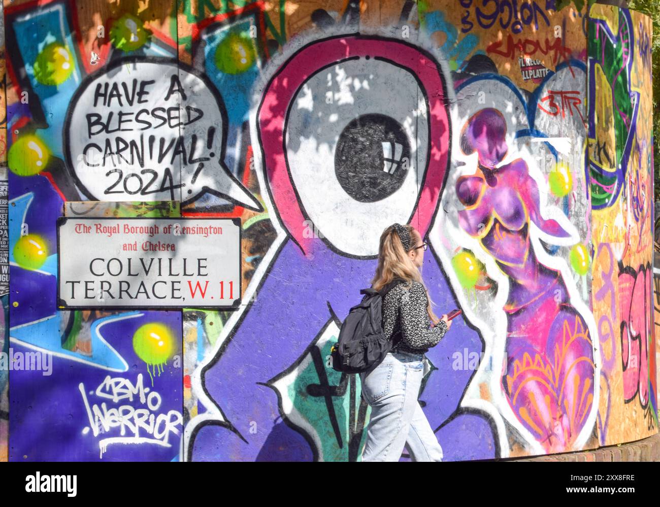 Londra, Inghilterra, Regno Unito. 23 agosto 2024. Una donna cammina davanti alle case a bordo prima del Carnevale di Notting Hill, che si svolge il 25 e 26 agosto. (Credit Image: © Vuk Valcic/ZUMA Press Wire) SOLO PER USO EDITORIALE! Non per USO commerciale! Foto Stock