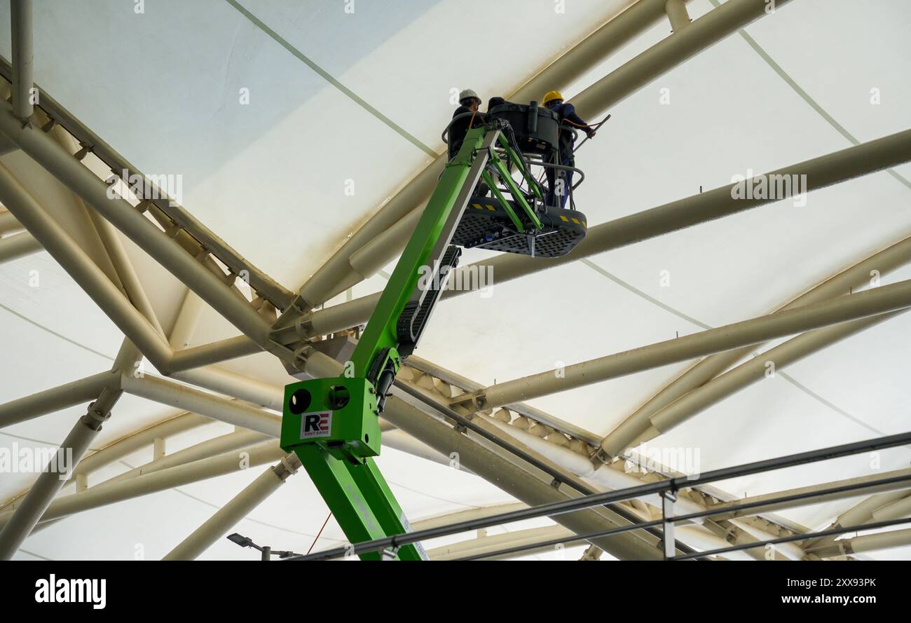 Nuova Delhi, India - 3 marzo 2024: I lavoratori su un ascensore lavano il tetto dell'edificio dell'aeroporto. Foto Stock