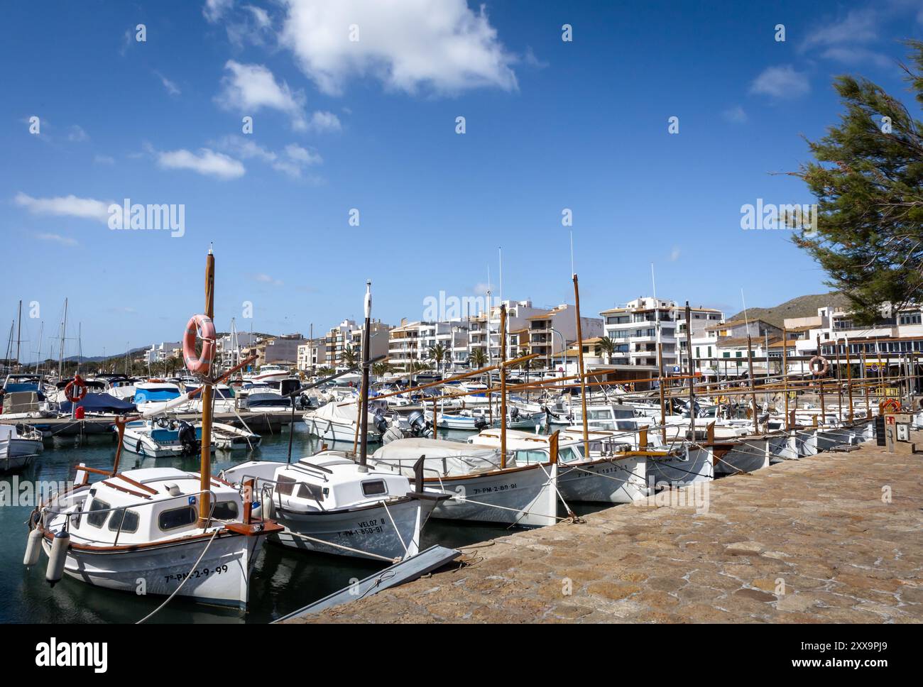Port de Pollenca, Maiorca, Spagna - 24 aprile 2024: Piccole barche da pesca nel porto e una passeggiata sul mare. Foto Stock