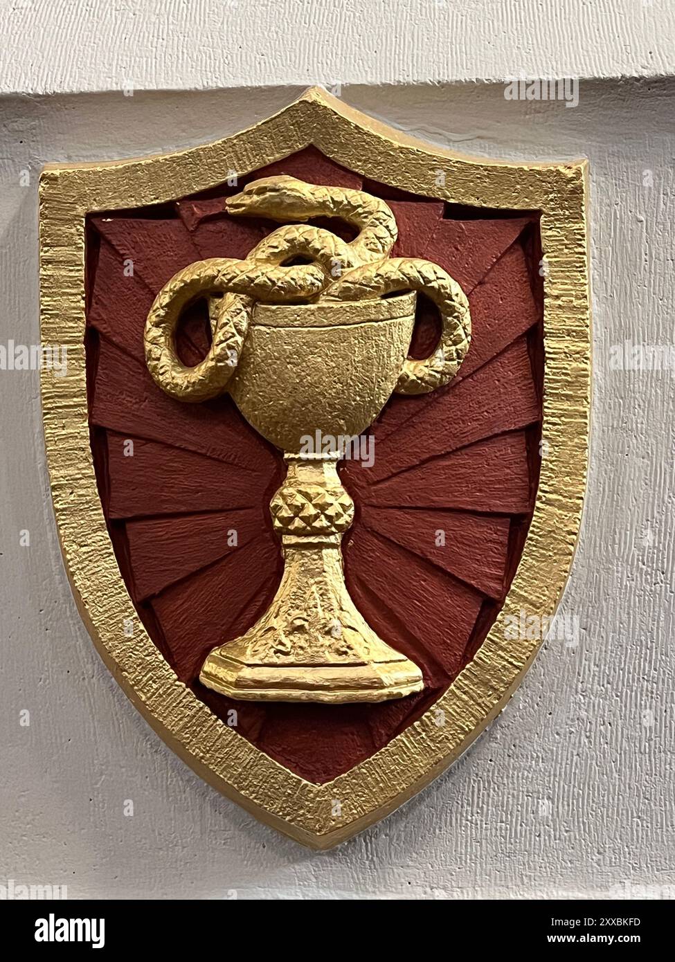 Serpente che esce da un calice come simbolo sul muro di una chiesa cattolica a Brooklyn, New York. Secondo la leggenda, a Giovanni Evangelista fu data una tazza di vino avvelenato che bevve senza danni. Come emblemi del racconto, il calice di Giovanni simboleggia la fede cristiana che prevale sulla morte, rappresentata dal serpente. Foto Stock