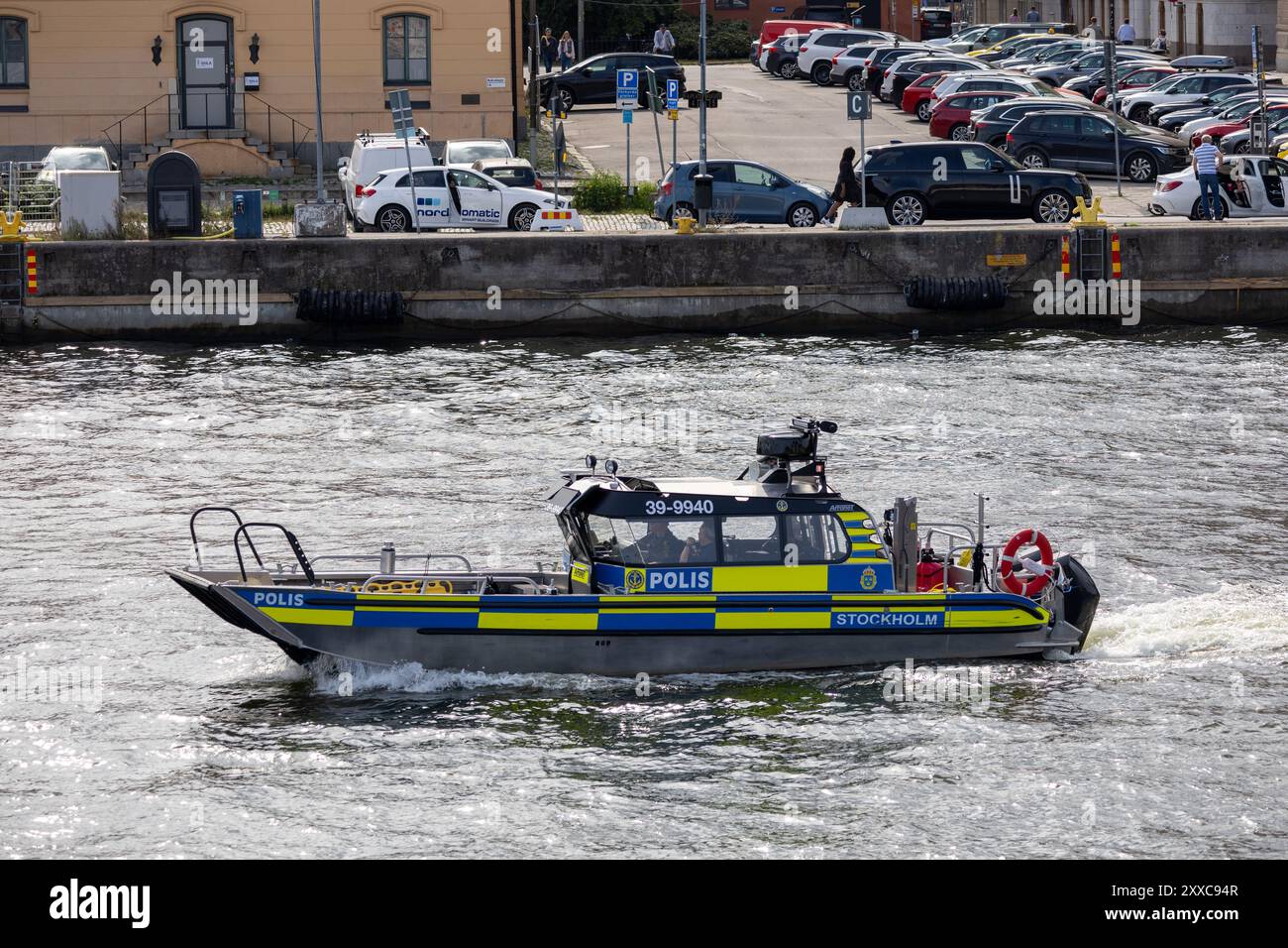 Una barca della polizia che naviga su un fiume a Stoccolma, in Svezia. La barca è contrassegnata con "POLIS" e presenta una combinazione di colori blu e giallo. Sullo sfondo, par Foto Stock