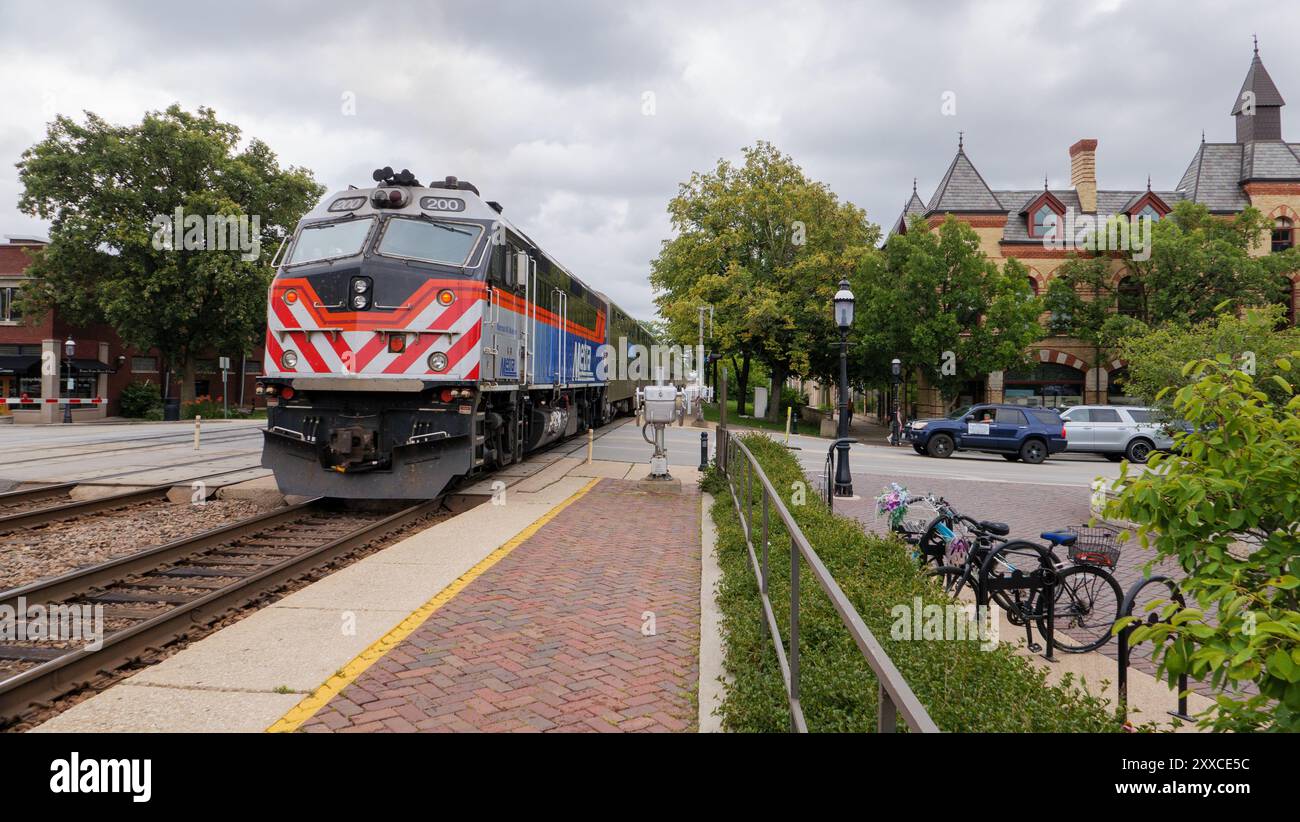 Treno pendolare BNSF Metra in entrata spinto da una locomotiva F40PHM-3 in uscita dalla stazione di Riverside, Illinois. Foto Stock