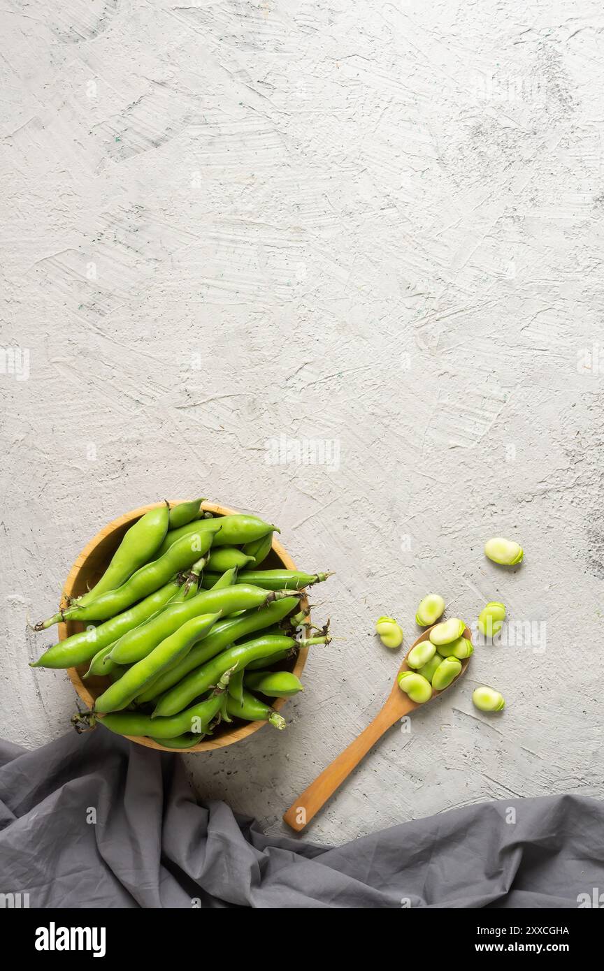 Fave fresche con baccello su fondo rustico, cibo sano Foto Stock