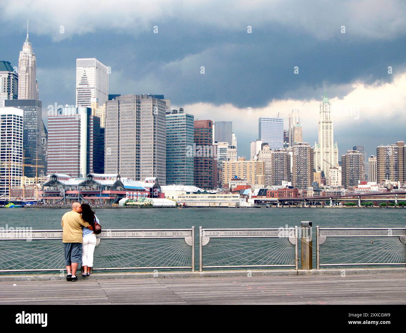 Coppia che condivide un bacio sul Fulton Landing con lo skyline di Manhattan sullo sfondo. Foto Stock