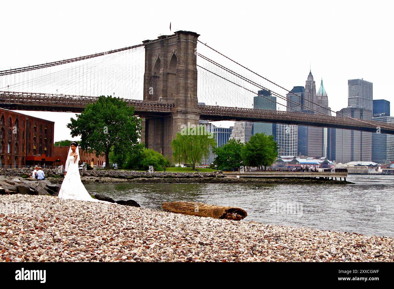 Una coppia di sposi che cammina sulla spiaggia di ciottoli nel Brooklyn Bridge Park nel quartiere DUMBO di Brooklyn Foto Stock