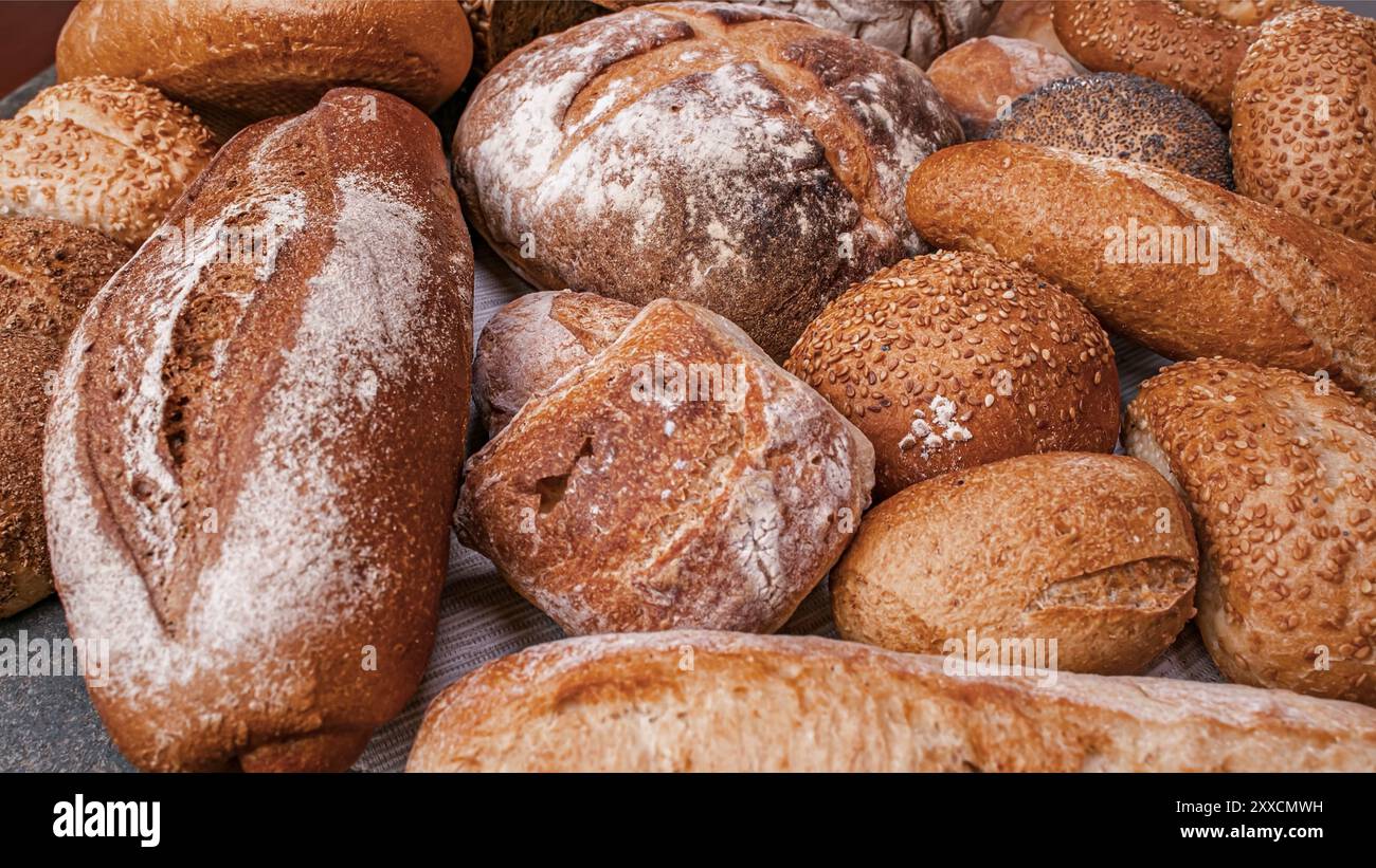Varietà di pane a lievitazione naturale su una pagnotta di legno di pane artigianale. Pane fresco e fragrante sul tavolo. Concetto alimentare . Diversi tipi di pane. Foto Stock