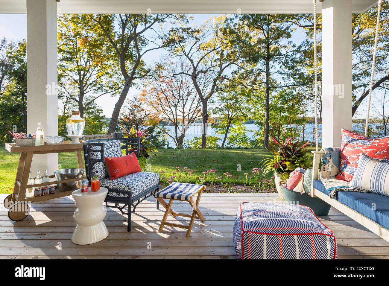 Veranda che si affaccia sul lago con un'altalena e una sedia e un carrello per bevande Foto Stock