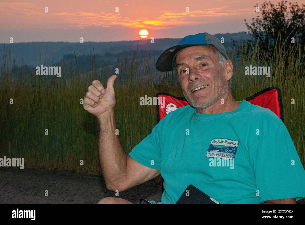 Un maschio adulto si rilassa mentre legge su un libro Kindle a Spring Mountain nella catena montuosa Blue Mountain dell'Oregon centrale. Foto Stock