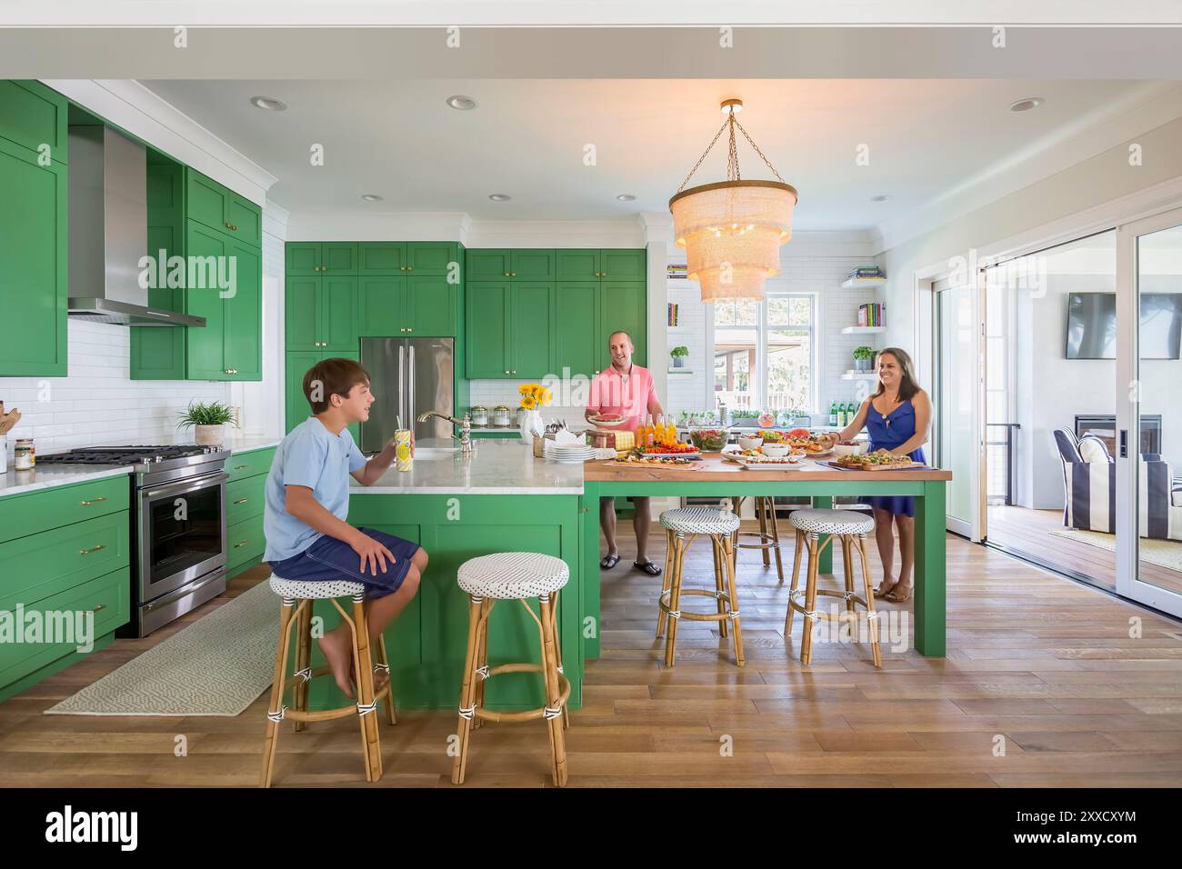 Una famiglia si trova in una cucina verde e luminosa, con molto spazio per riunirsi Foto Stock