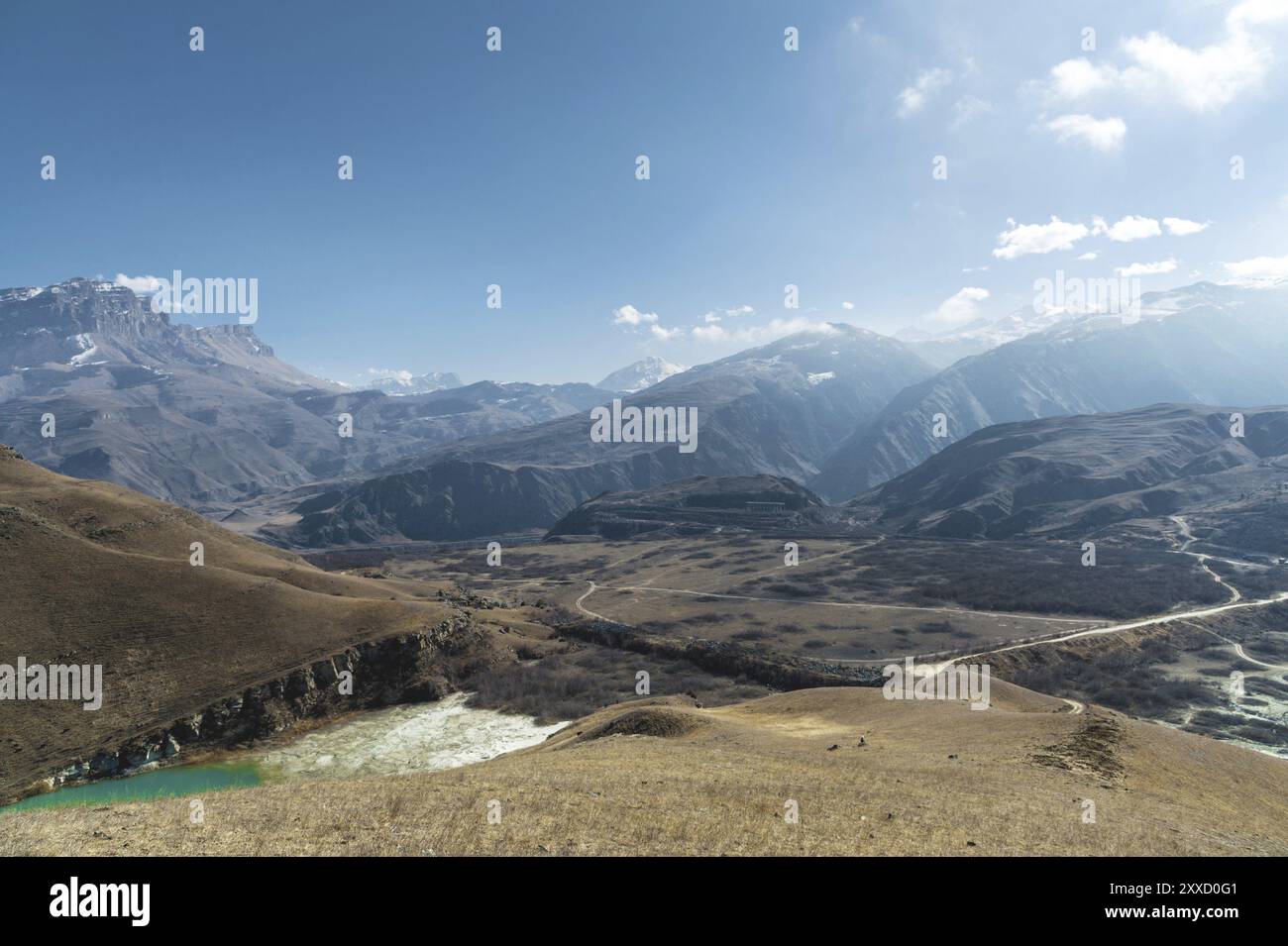 Paesaggio di alta montagna del Caucaso settentrionale. Un'istantanea dell'altezza di un lago e di una strada sterrata sullo sfondo. Cielo blu con nuvole Foto Stock