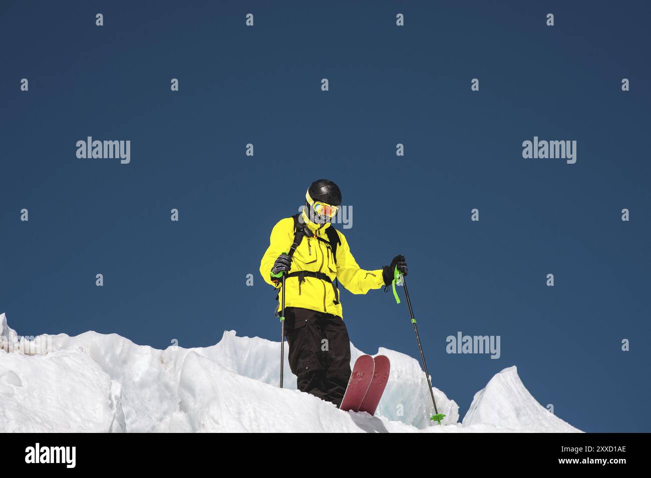 Un freerider sciatore in completo vestito si trova su un ghiacciaio nel Caucaso settentrionale. Sciatore che si prepara prima di saltare dal ghiacciaio Foto Stock