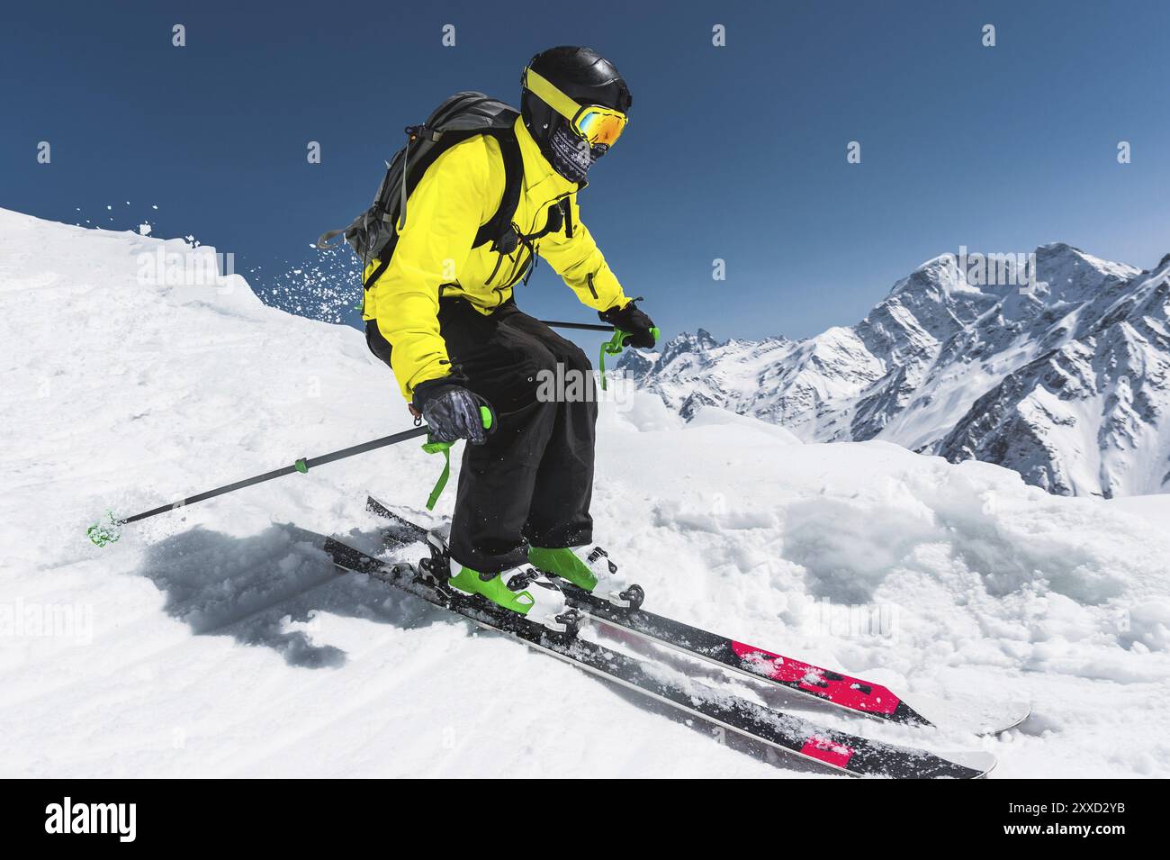 Sciatore professionista alla velocità prima di saltare dal ghiacciaio in inverno contro il cielo blu e le montagne Foto Stock