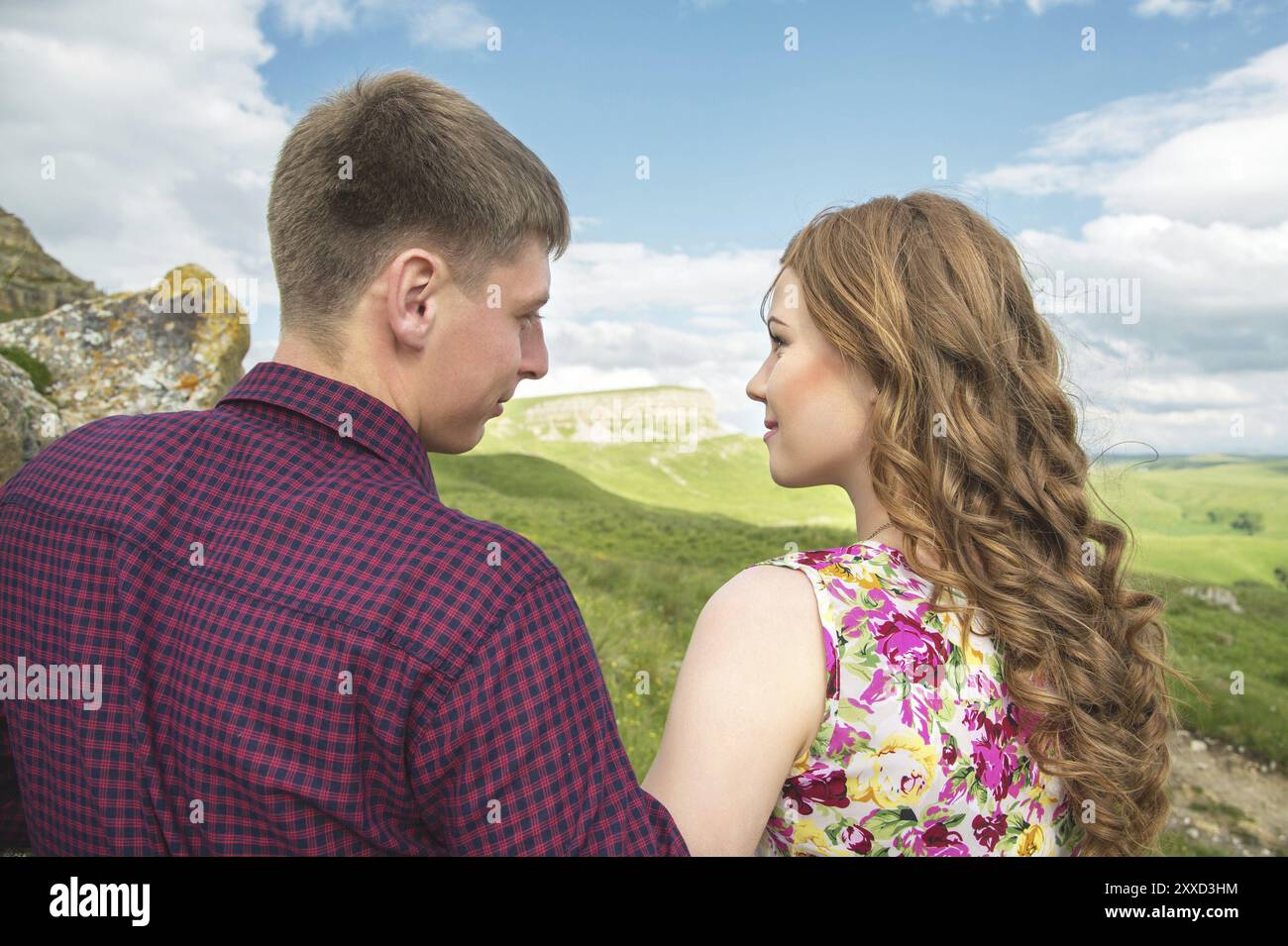 Una giovane coppia di sposi si mette in cerca di un bacio sullo sfondo di una bella natura. Concetto di una giovane famiglia felice Foto Stock