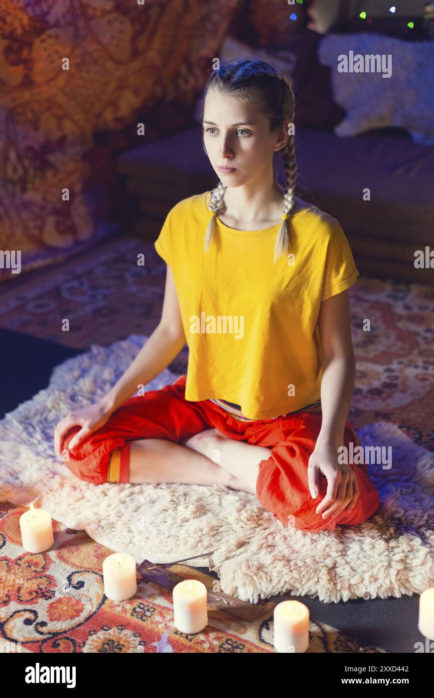 Primo piano della mano della donna in yoga lotus posa meditare in una stanza di artigianato con candele Foto Stock