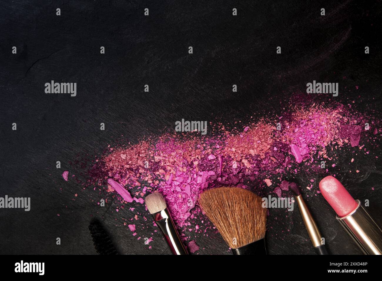 Make-up pennelli e rossetto con rotture di cosmetici, overhead shot su uno sfondo nero con copia spazio, una bellezza modello di progettazione per un banner per il trucco Foto Stock