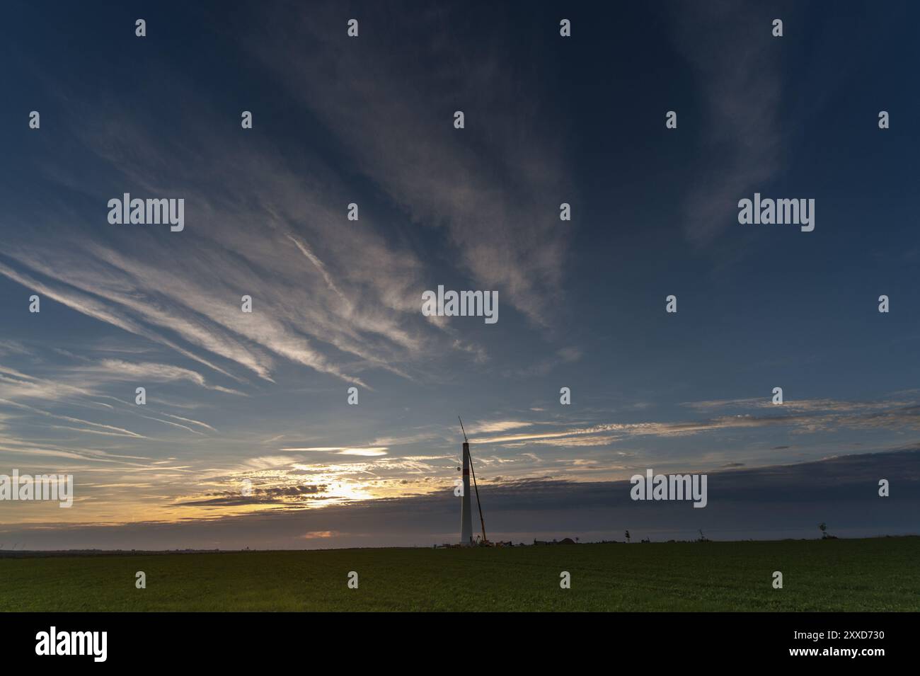 L'albero di una turbina eolica si trova da solo all'orizzonte Foto Stock