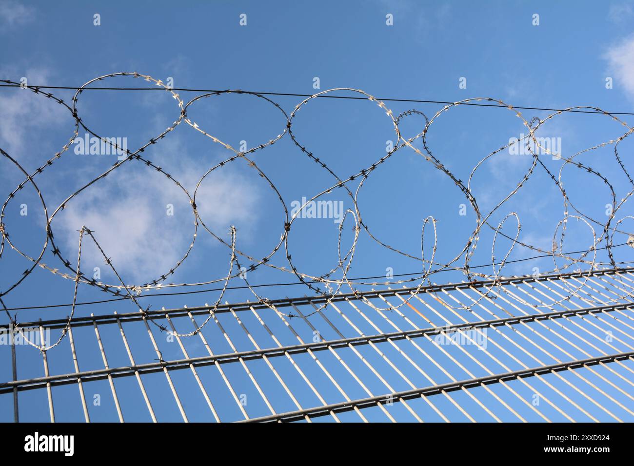 Filo spinato su una recinzione alta Foto Stock