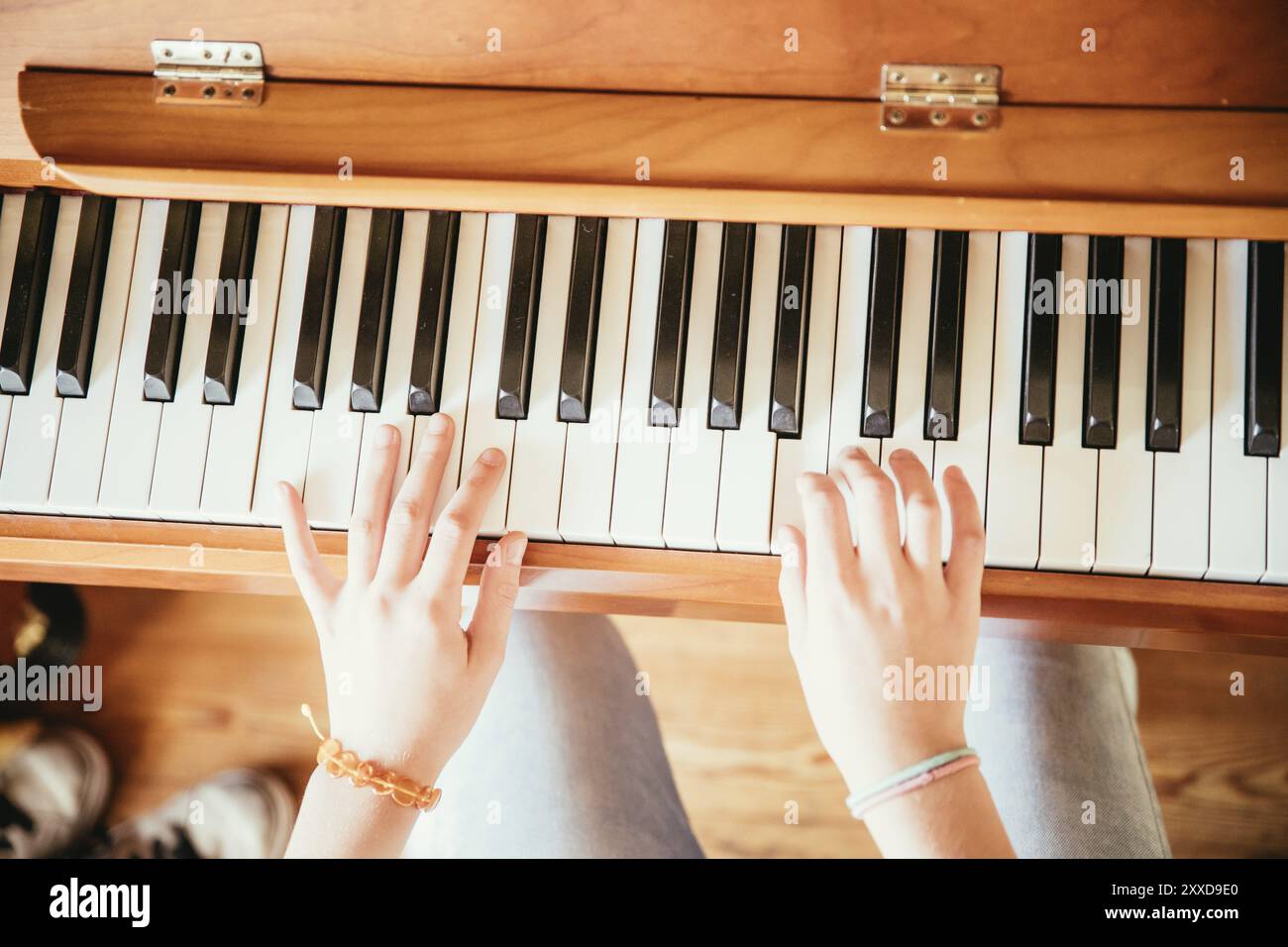 La giovane ragazza sta praticando il pianoforte a casa. Ritaglio di pianoforte e mani Foto Stock