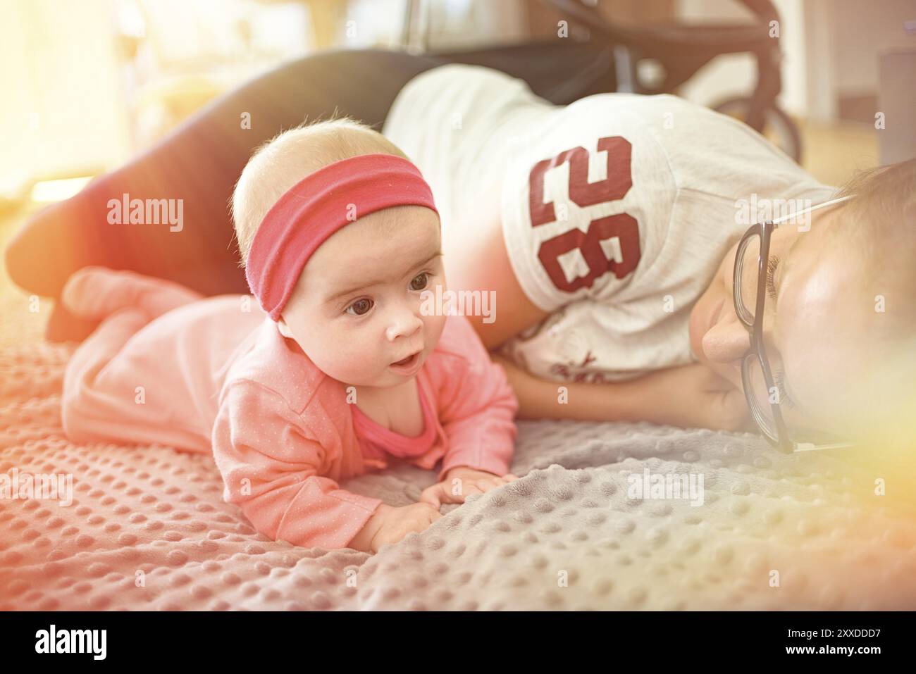 Ritratto di carino di 5 settimane di età baby ragazza distesa con la madre sul pavimento in brigkt soggiorno. Baby Care concept Foto Stock