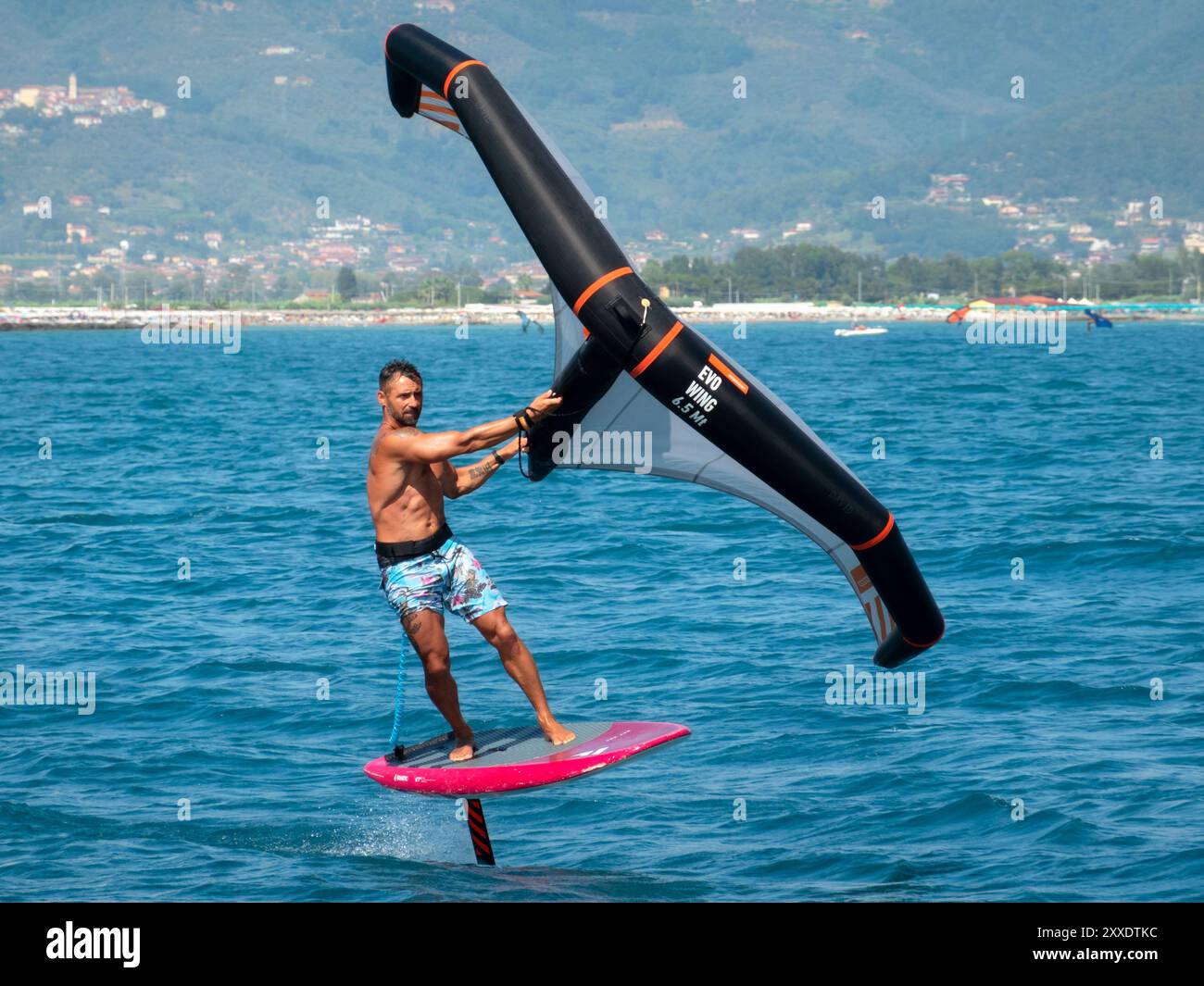 Fiumaretta di Ameglia, Italia - 22 agosto 2024: L'uomo pratica la lamina alare nel mare ligure. Wing foil è uno sport acquatico dinamico che combina surf e k Foto Stock