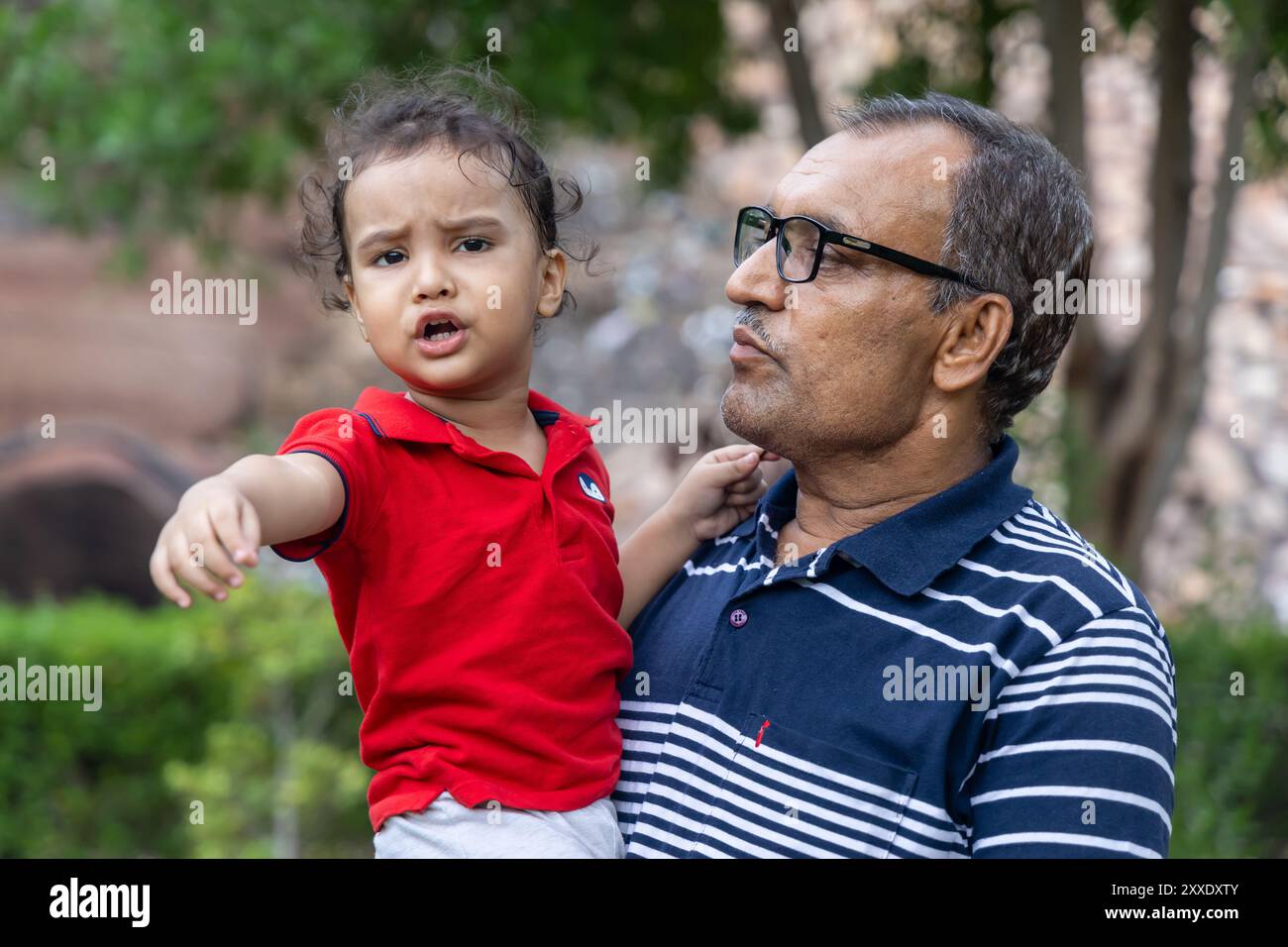 Nonno che conforta il nipote irritato nel parco all'aperto di Dusk Foto Stock