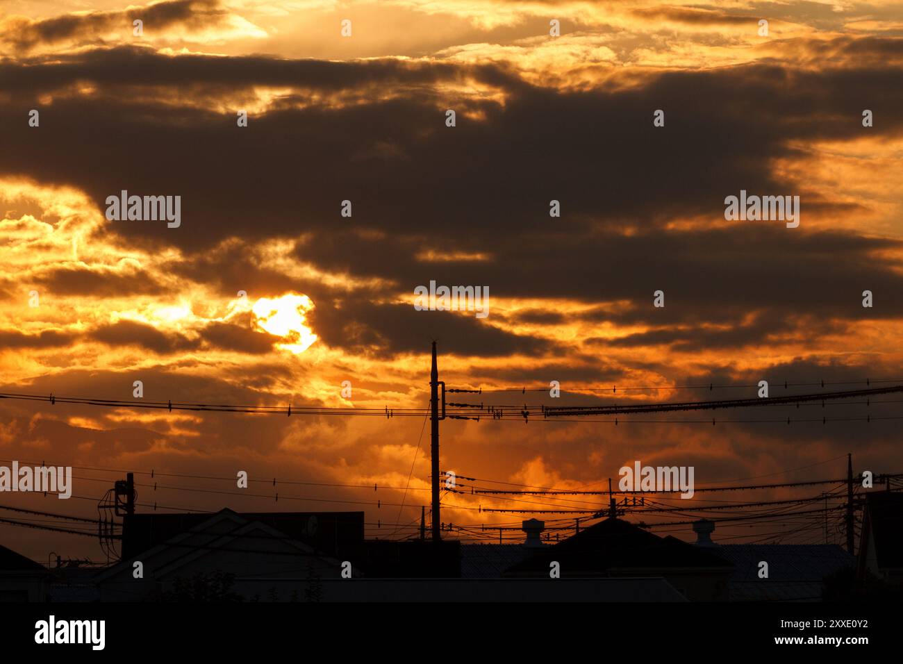 Un tramonto in un cielo nuvoloso sopra case e pali del telegrafo a Kanagawa, Giappone. Foto Stock