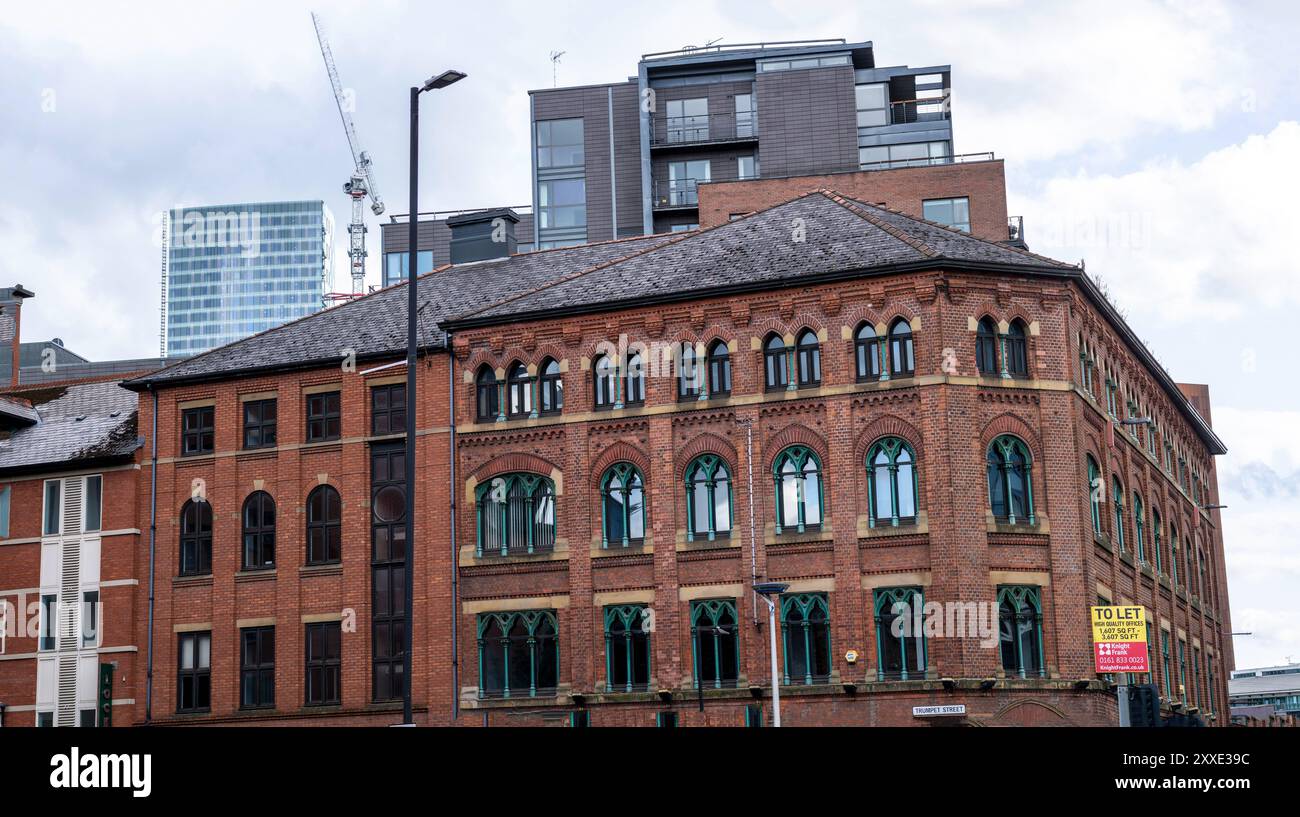Due edifici adiacenti a Manchester, Regno Unito. Uno è fatto di pietra beige e l'altro ha un aspetto industriale. Foto Stock
