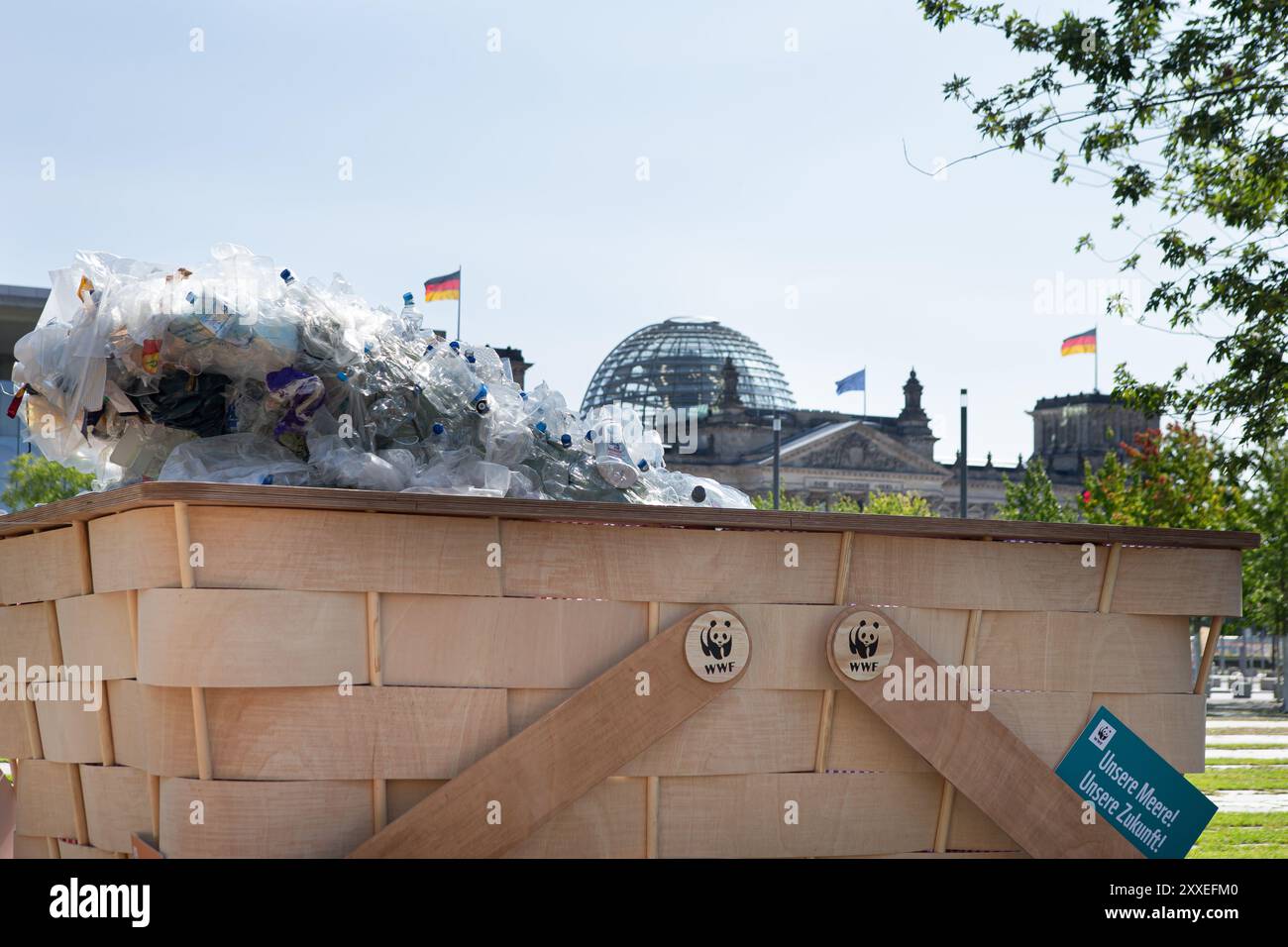 Berlino, Germania, 24 settembre 2024. Gli attivisti ambientalisti prendono parte a un picnic di protesta a livello nazionale organizzato dal WWF Germany contro la crisi plastica di fronte alla Cancelleria federale di Berlino. I manifestanti si riuniscono con striscioni colorati e un gigantesco cestino simbolico da picnic pieno di rifiuti di plastica, chiedendo un forte trattato globale delle Nazioni Unite per porre fine all'inquinamento della plastica durante i negoziati ONU in corso. Felix Wolf/Alamy Live News Foto Stock