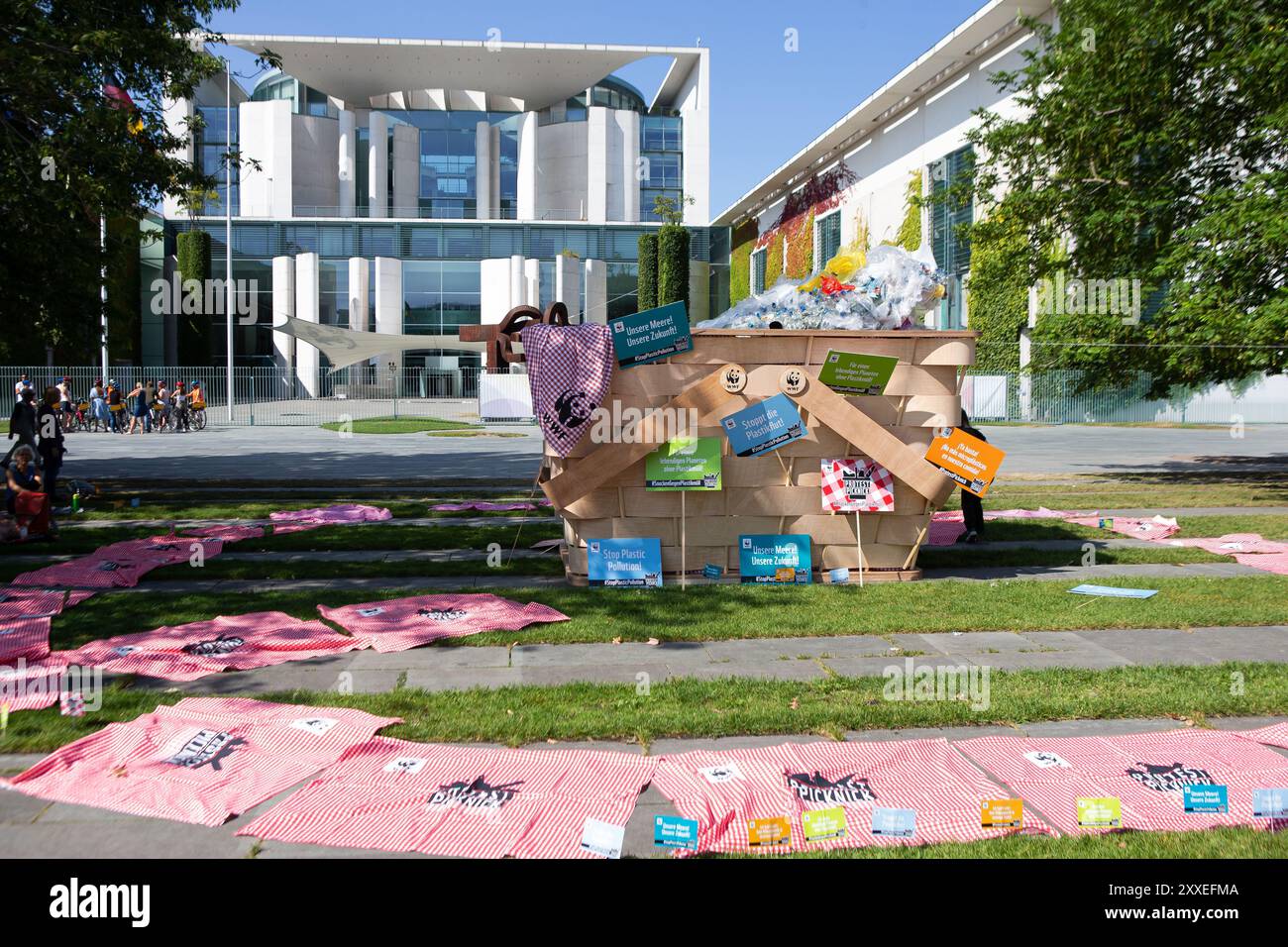 Berlino, Germania, 24 settembre 2024. Gli attivisti ambientalisti prendono parte a un picnic di protesta a livello nazionale organizzato dal WWF Germany contro la crisi plastica di fronte alla Cancelleria federale di Berlino. I manifestanti si riuniscono con striscioni colorati e un gigantesco cestino simbolico da picnic pieno di rifiuti di plastica, chiedendo un forte trattato globale delle Nazioni Unite per porre fine all'inquinamento della plastica durante i negoziati ONU in corso. Felix Wolf/Alamy Live News Foto Stock