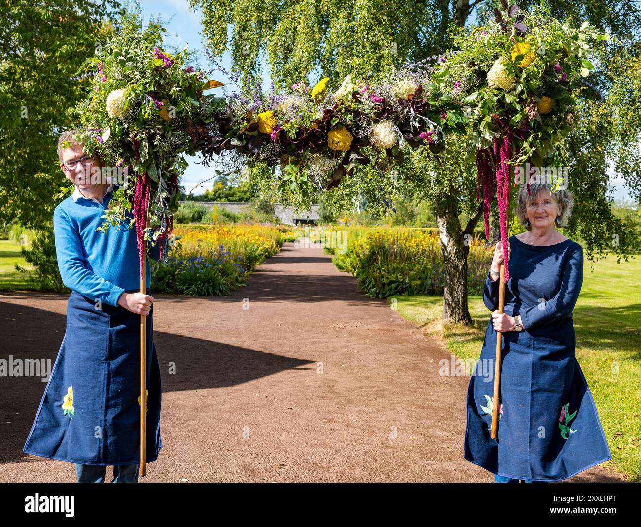 Giardino recintato di Amisfield, Haddington, East Lothian, Scozia, Regno Unito. Scotland's Gardens Scheme Free Gardeners: Un grande giardino murato del XVIII secolo segna la storia dell'ordine dei giardinieri liberi, una società fraterna fondata nel XVII secolo. La prova più antica è la loggia di Haddington aperta nel 1676. I primi membri della loggia erano piccoli proprietari terrieri e agricoltori che praticavano il giardinaggio per piacere, come un primo sindacato. Nella foto: Owen e Carol, volontari del giardino portano un boccaglio di fiori. Crediti: Sally Anderson/Alamy Live News Foto Stock