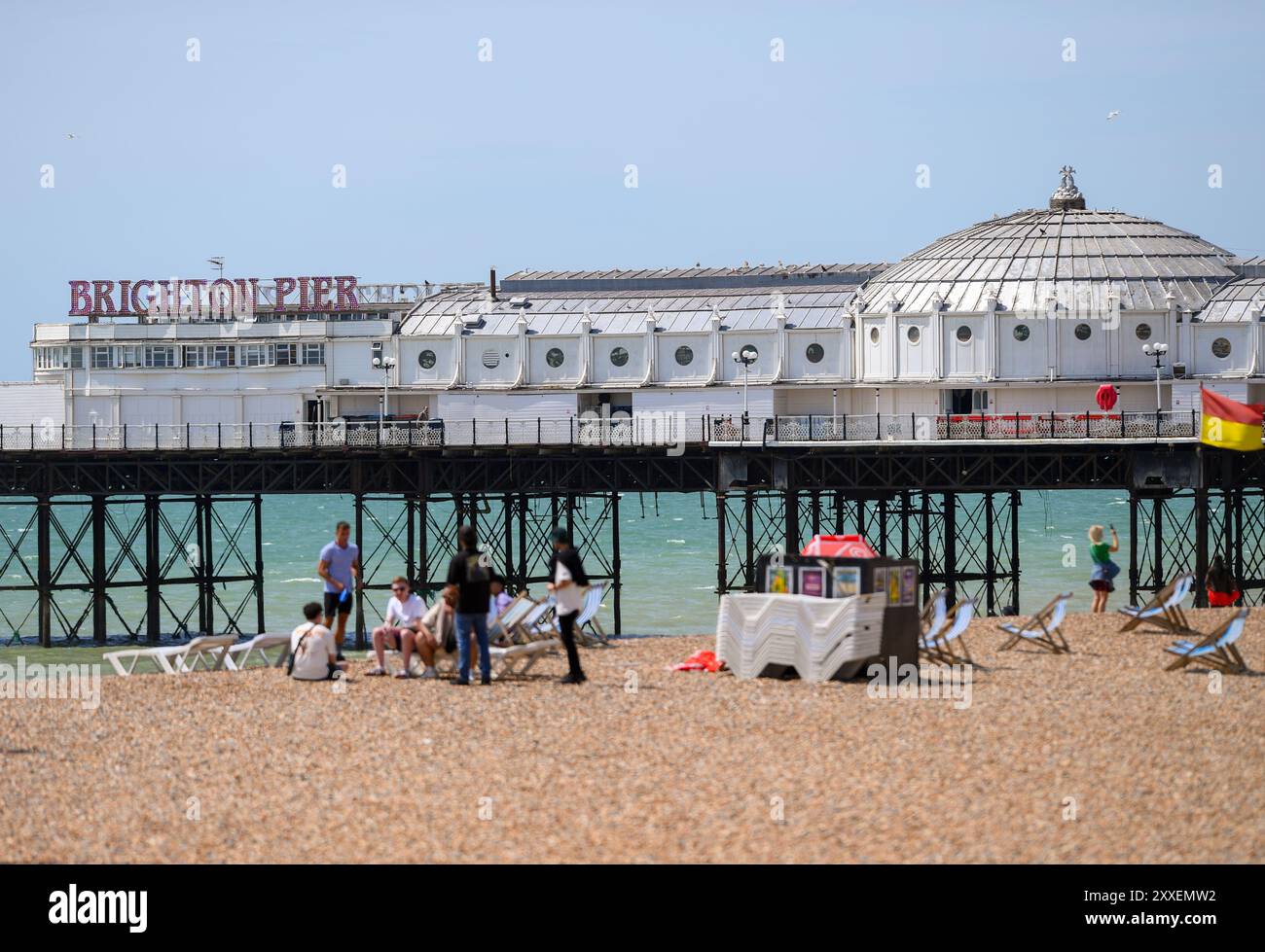 Vista sul lato sinistro del molo di Brighton scattata con un teleobiettivo con una spiaggia tranquilla con un numero limitato di persone in una giornata di sole. Foto Stock