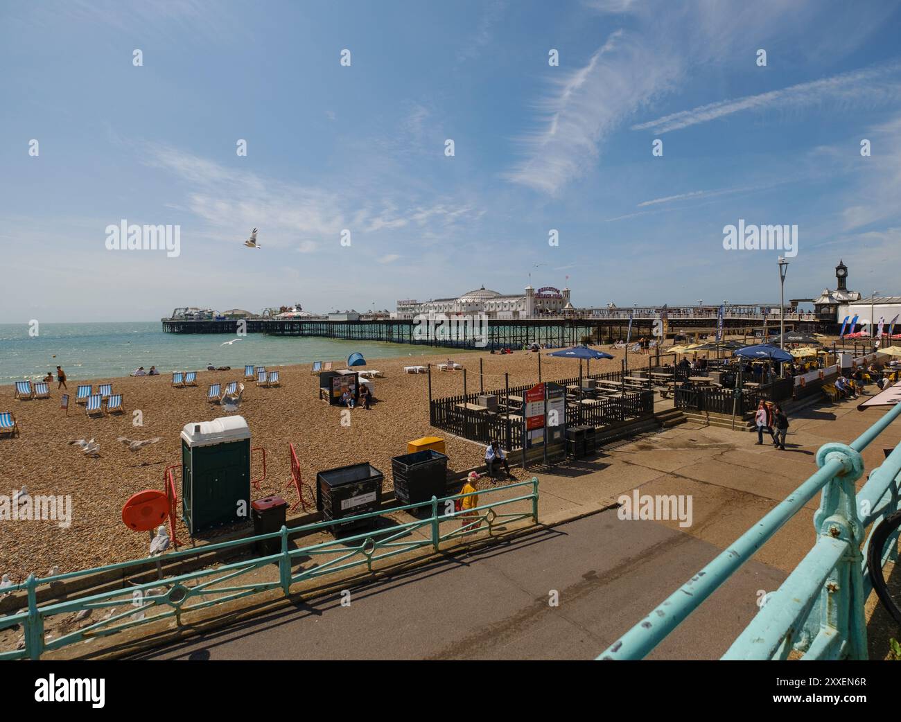Una vista panoramica del Brighton Pier England presa dal lato sinistro del molo che mostra la spiaggia e il caffè in primo piano con rampa di accesso alla spiaggia. Foto Stock