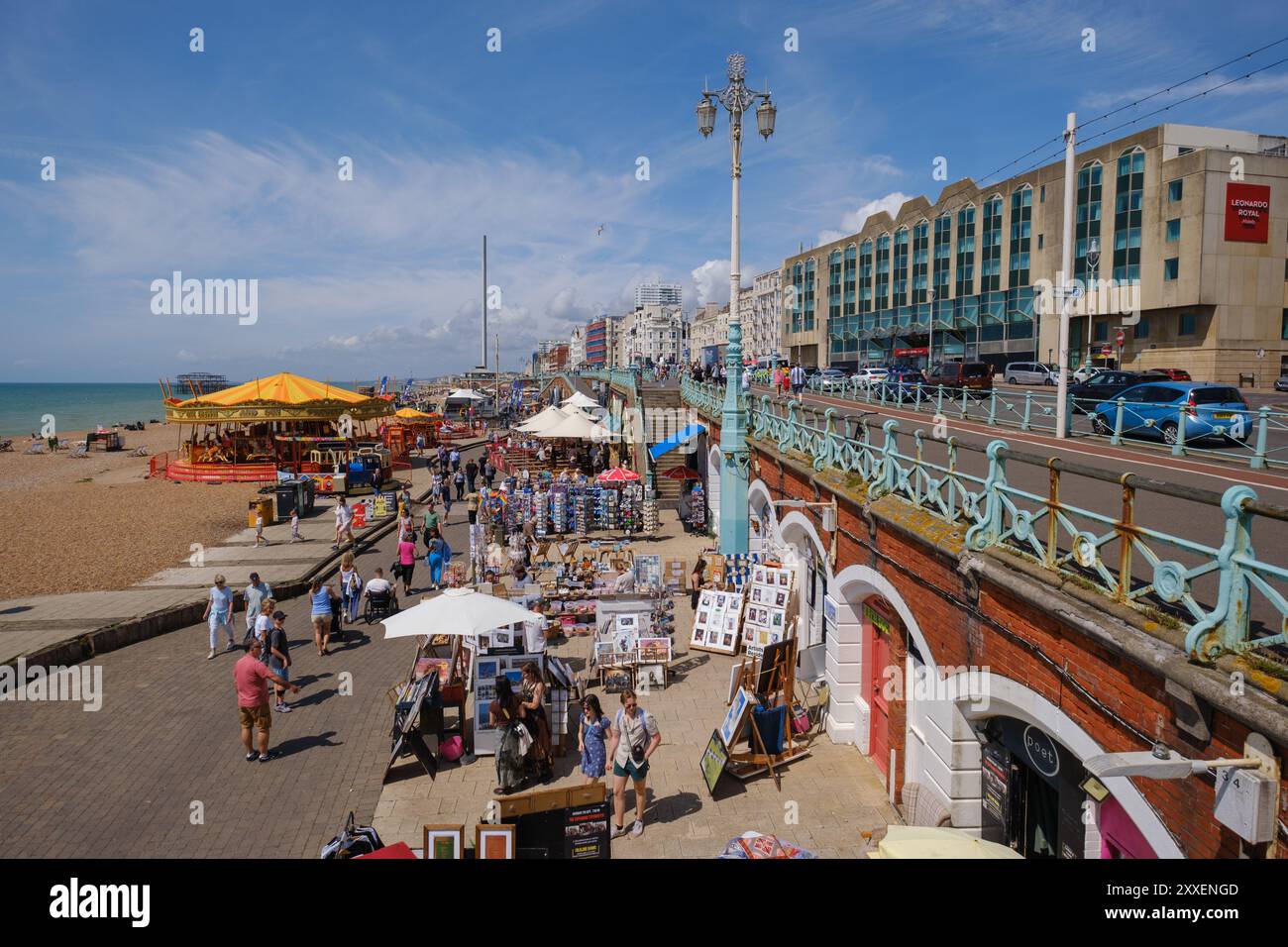 Passeggiata sulla spiaggia di Brighton che mostra la giostra della fiera e i negozi degli archi di Kings Road Foto Stock