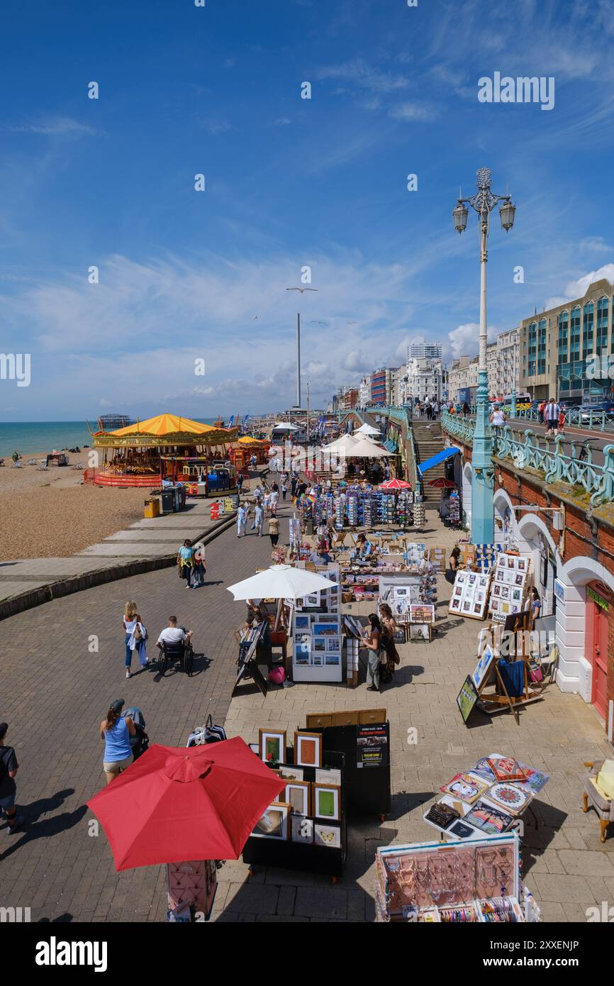 Passeggiata sulla spiaggia di Brighton che mostra la giostra della fiera e i negozi degli archi di Kings Road Foto Stock