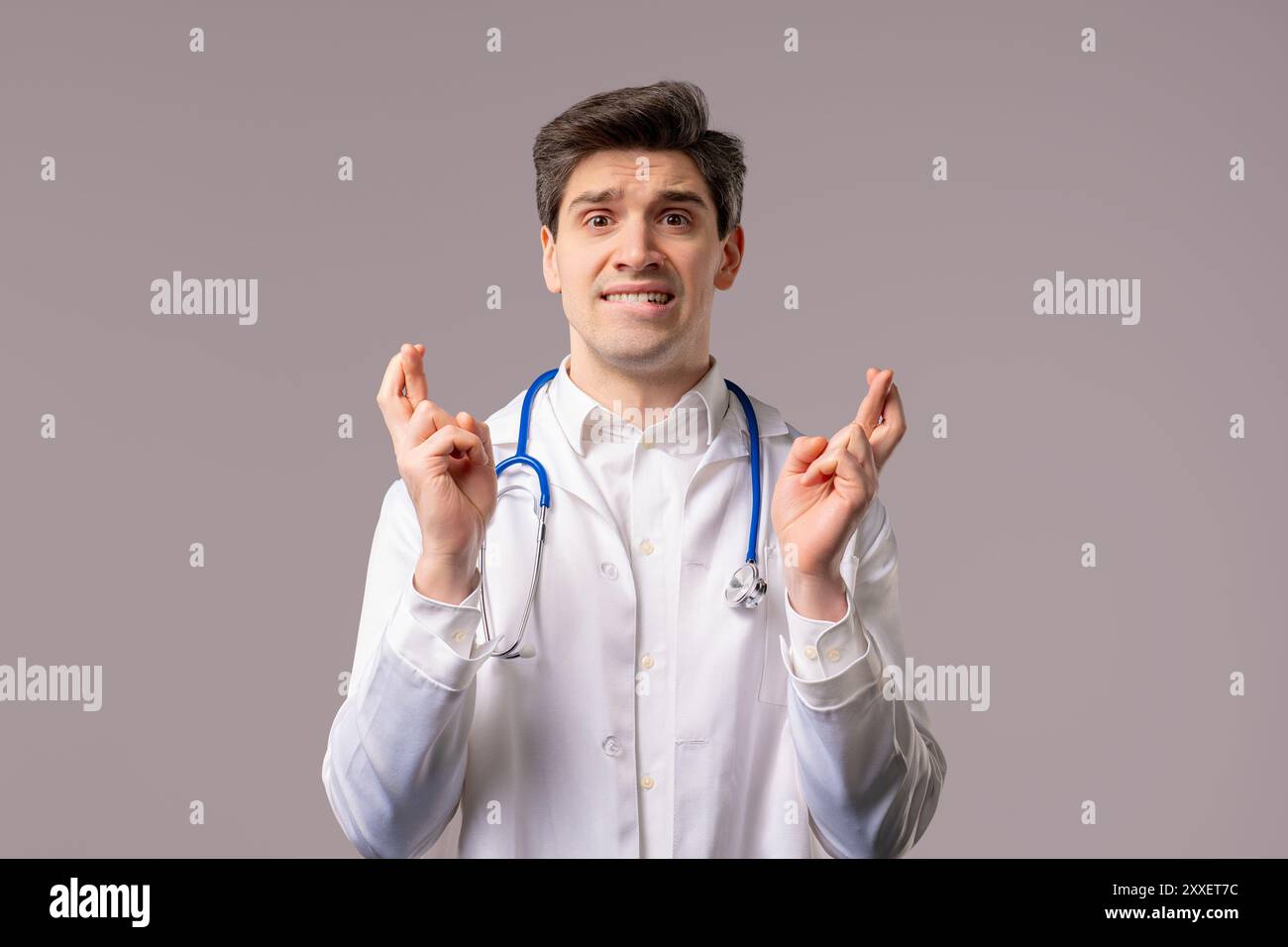 Adulto 30 anni medico uomo in forma di cappotto medico bianco che prega con le dita su sfondo bianco. Supplica che qualcuno soddisfi i desideri, aiuti, prega per Foto Stock