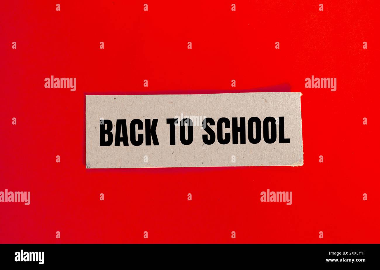 Messaggio di ritorno a scuola scritto su un pezzo di carta con sfondo rosso. Simbolo concettuale di ritorno a scuola. Copia spazio. Foto Stock