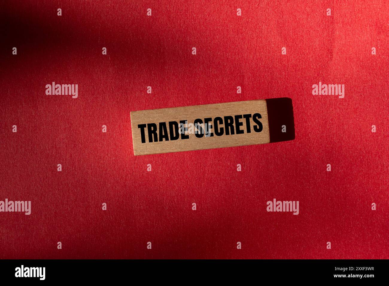 Messaggio segreto commerciale scritto su blocco di legno con sfondo rosso. Simbolo dei segreti commerciali concettuali. Copia spazio. Foto Stock